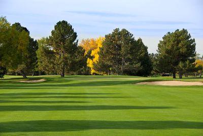 Golf course fairway with green grass, sand bunkers on both sides, and trees with some autumn foliage in the background.
