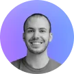 Smiling man with short hair and beard in front of a purple and blue gradient background.