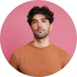 A man standing in front of a pink background.