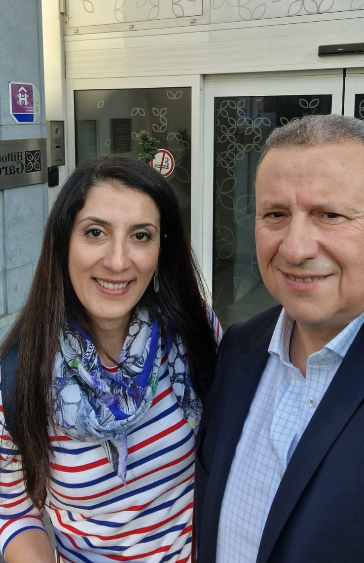 Two people chatting at a table with snowy mountains visible through the window