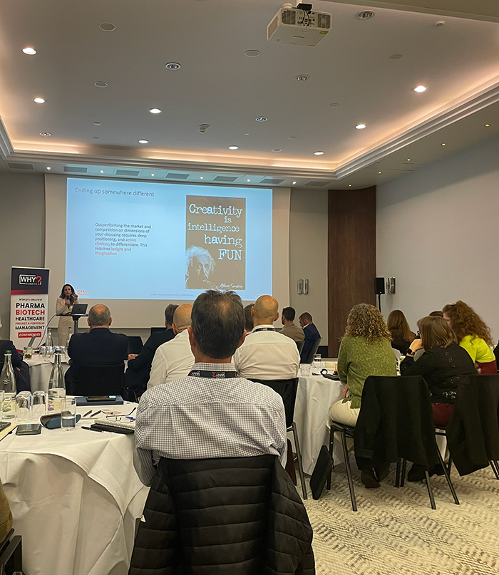 Four people working on laptops around a table in a bright room with snowy trees outside the window