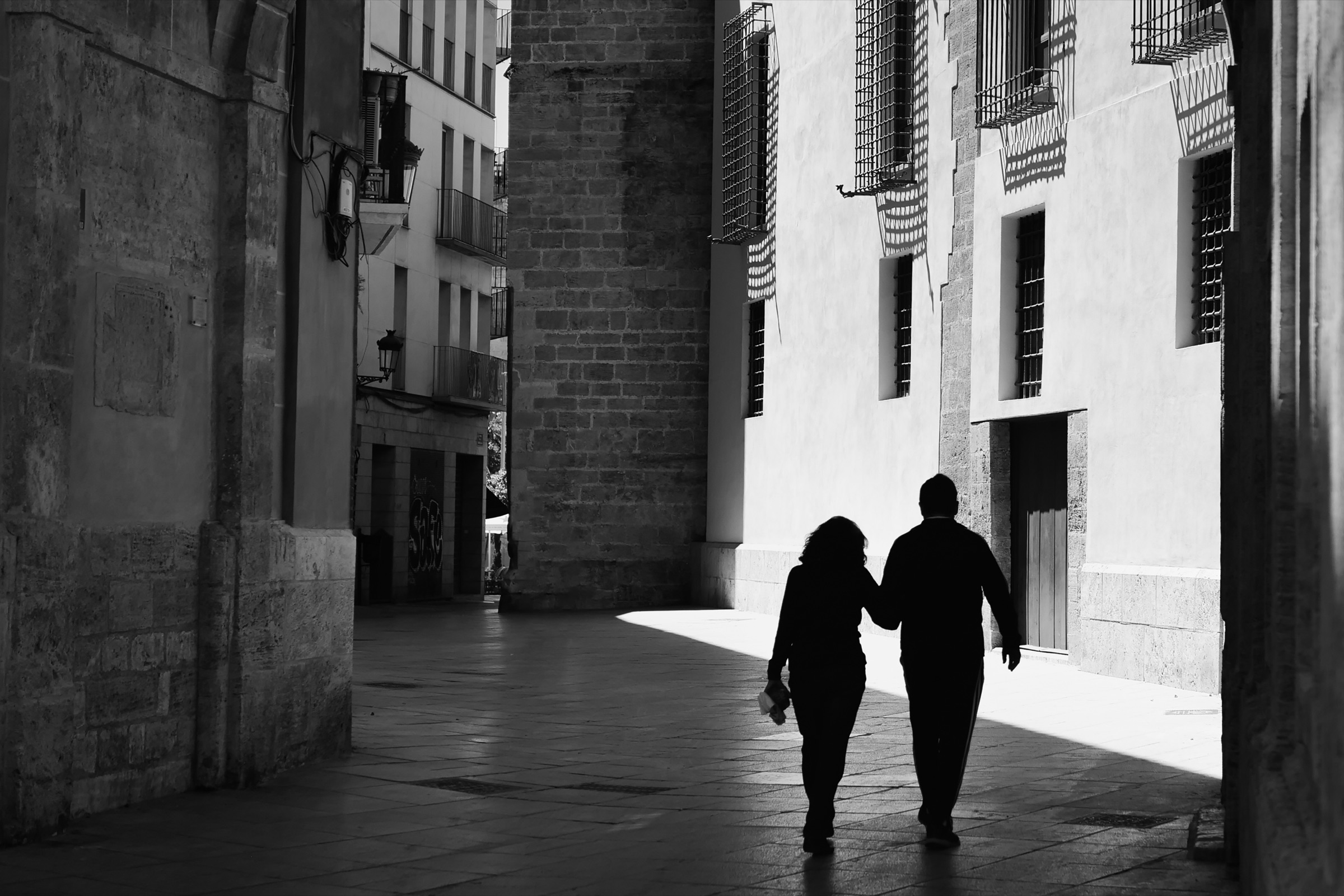 A couple walking hand in hand through a quiet European street
