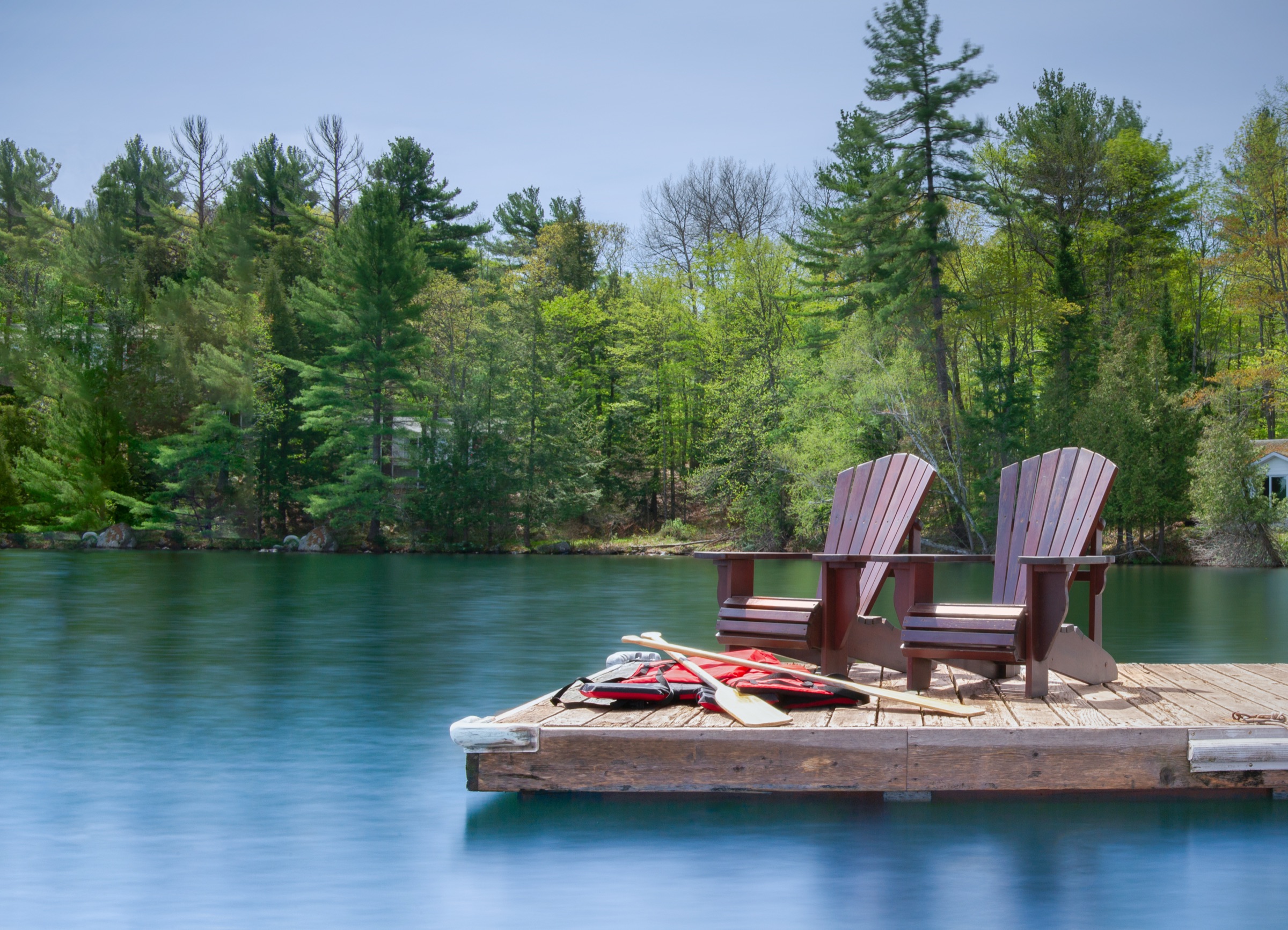 Two chairs on a wooden dock overlooking calm water