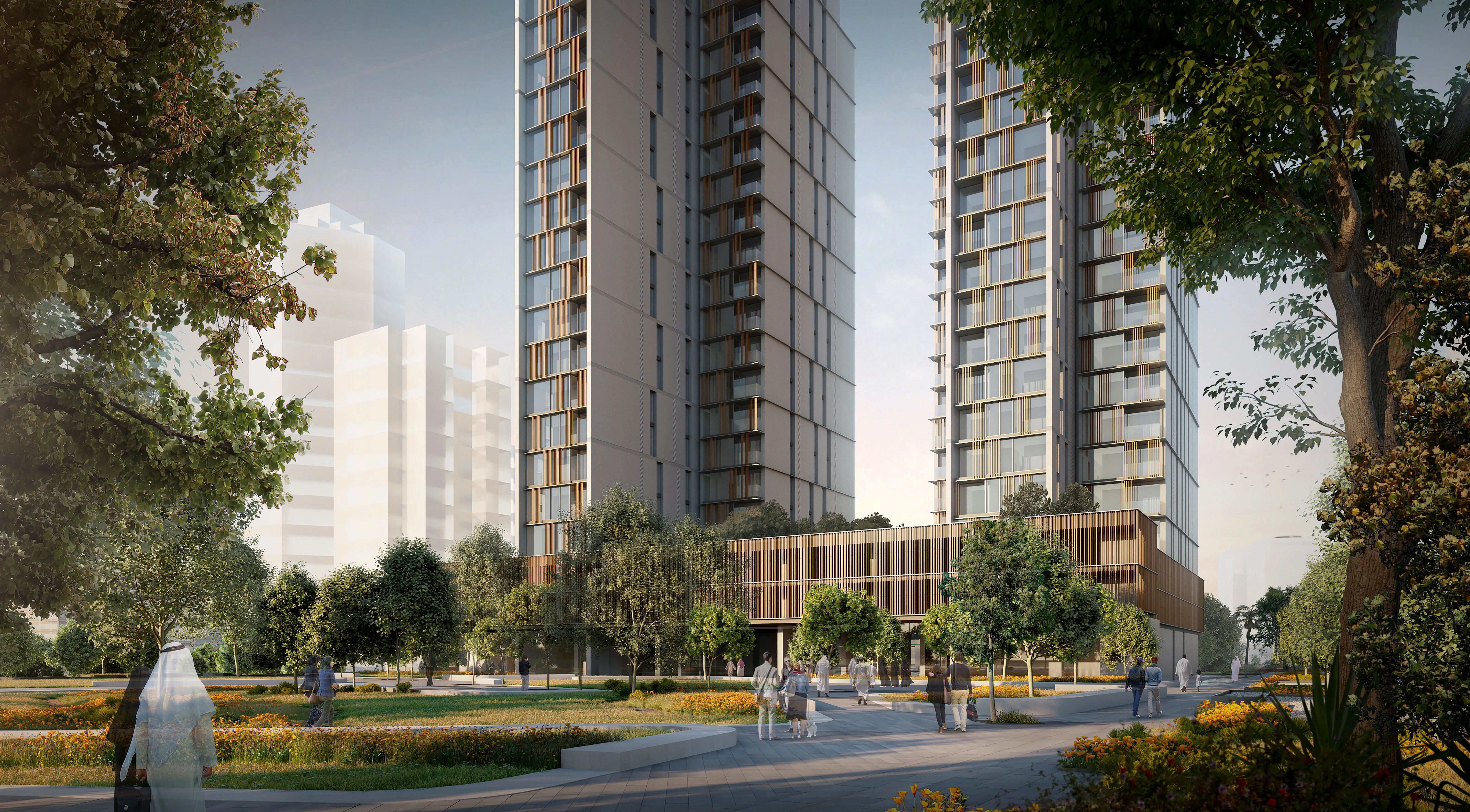 Twin residential towers of Hessah Al Mubarak in Kuwait City rising above a landscaped podium with trees and pedestrians on tree-lined pathways