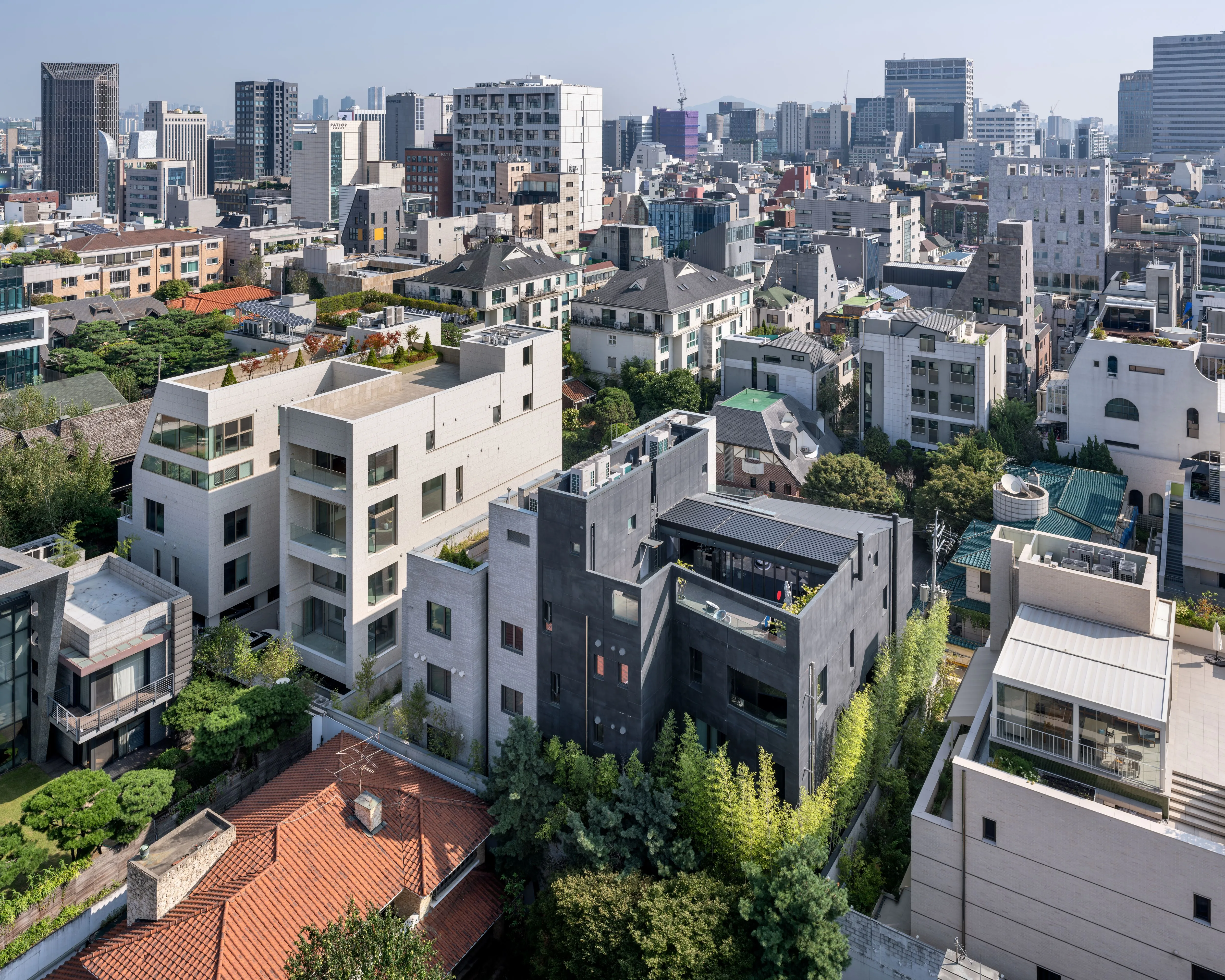 Aerial view of Pyrite's dark chiseled concrete volume standing among white townhouses and dense rooftops in a residential district of Seoul