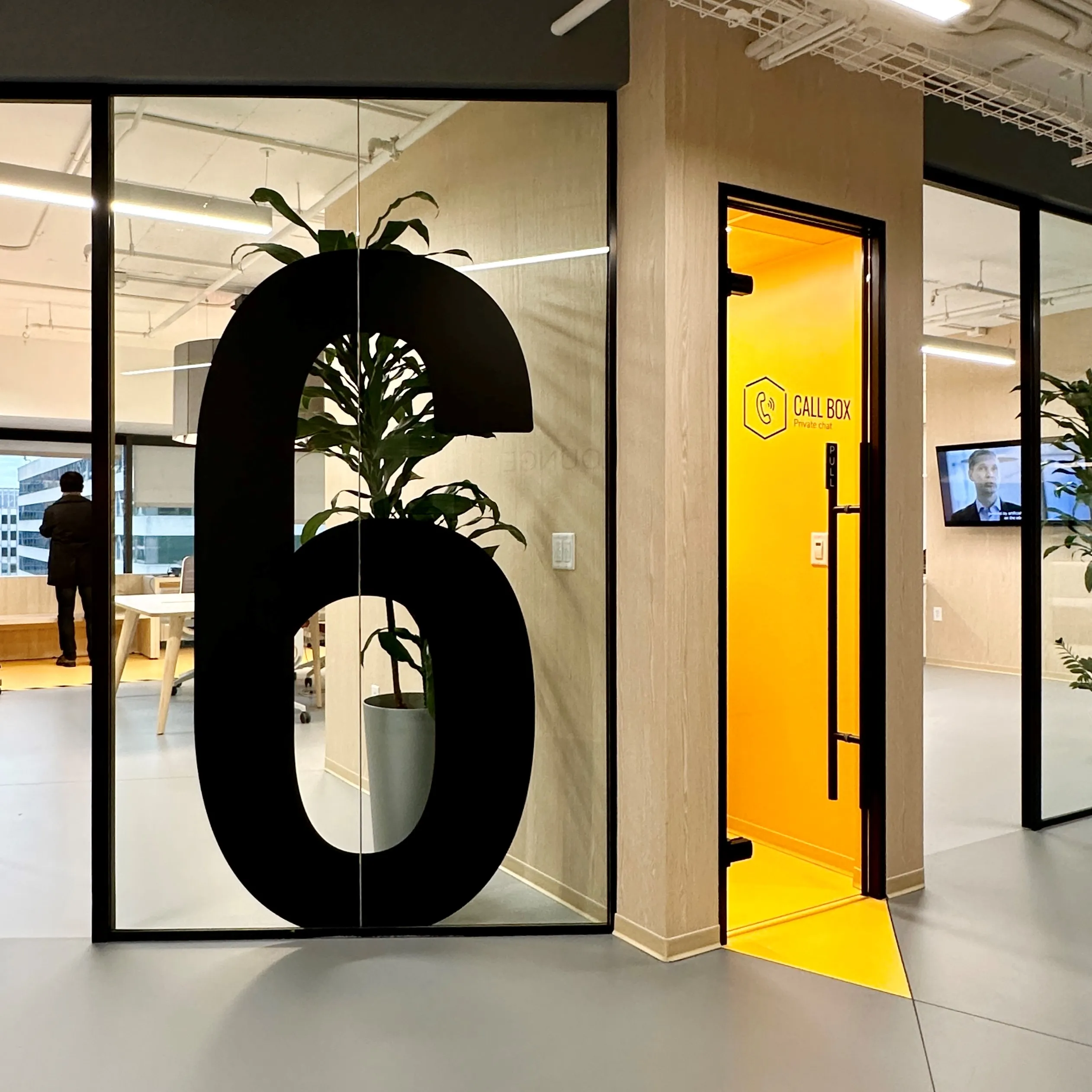 Interior of Zebox Washington in Washington D.C., a glazed lounge with a large numeral 6 decal and a bright yellow private call box beyond
