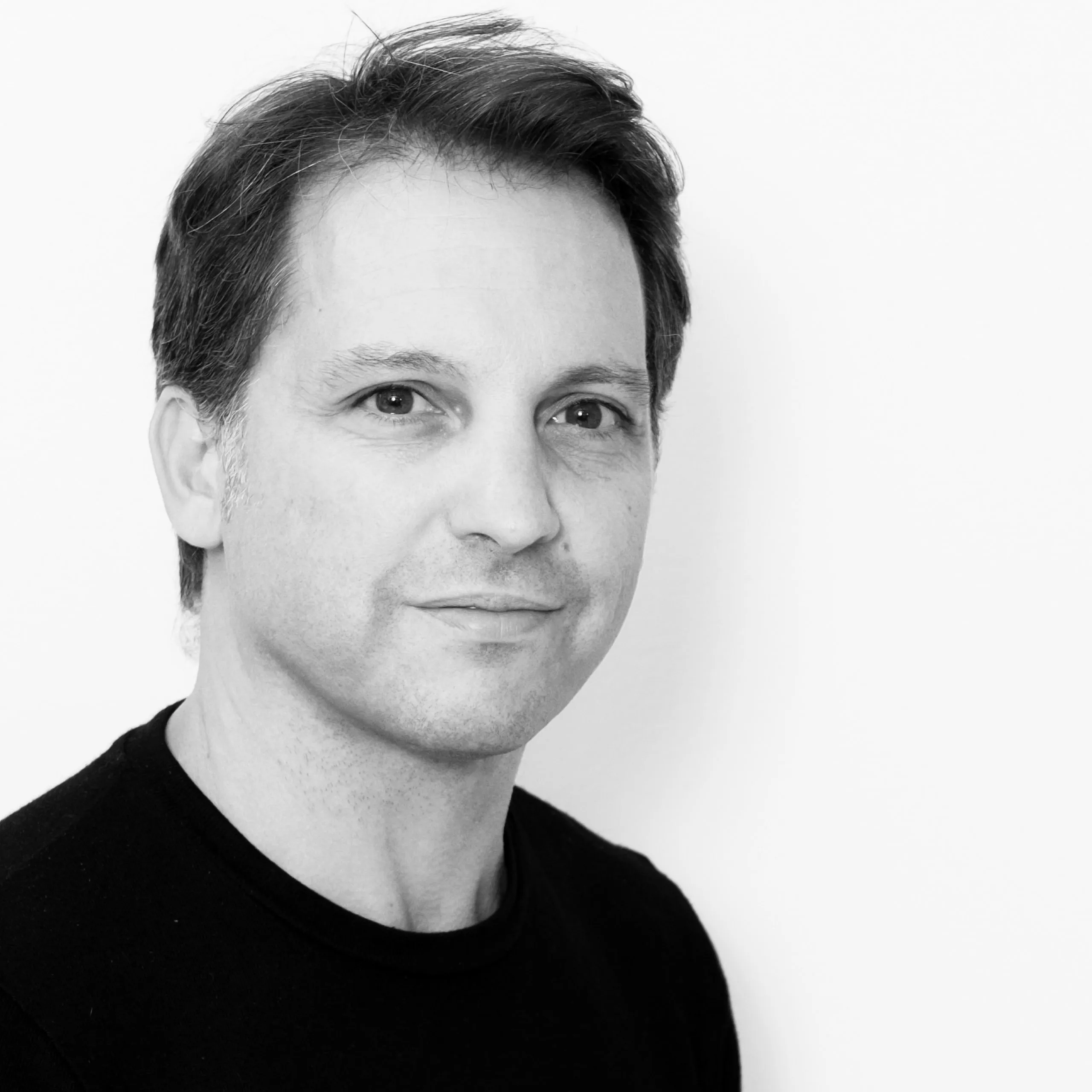 Daniel Perez, Senior Architect and Head of Design at Nabil Gholam Architects, black and white portrait in a black crew-neck top against a plain background