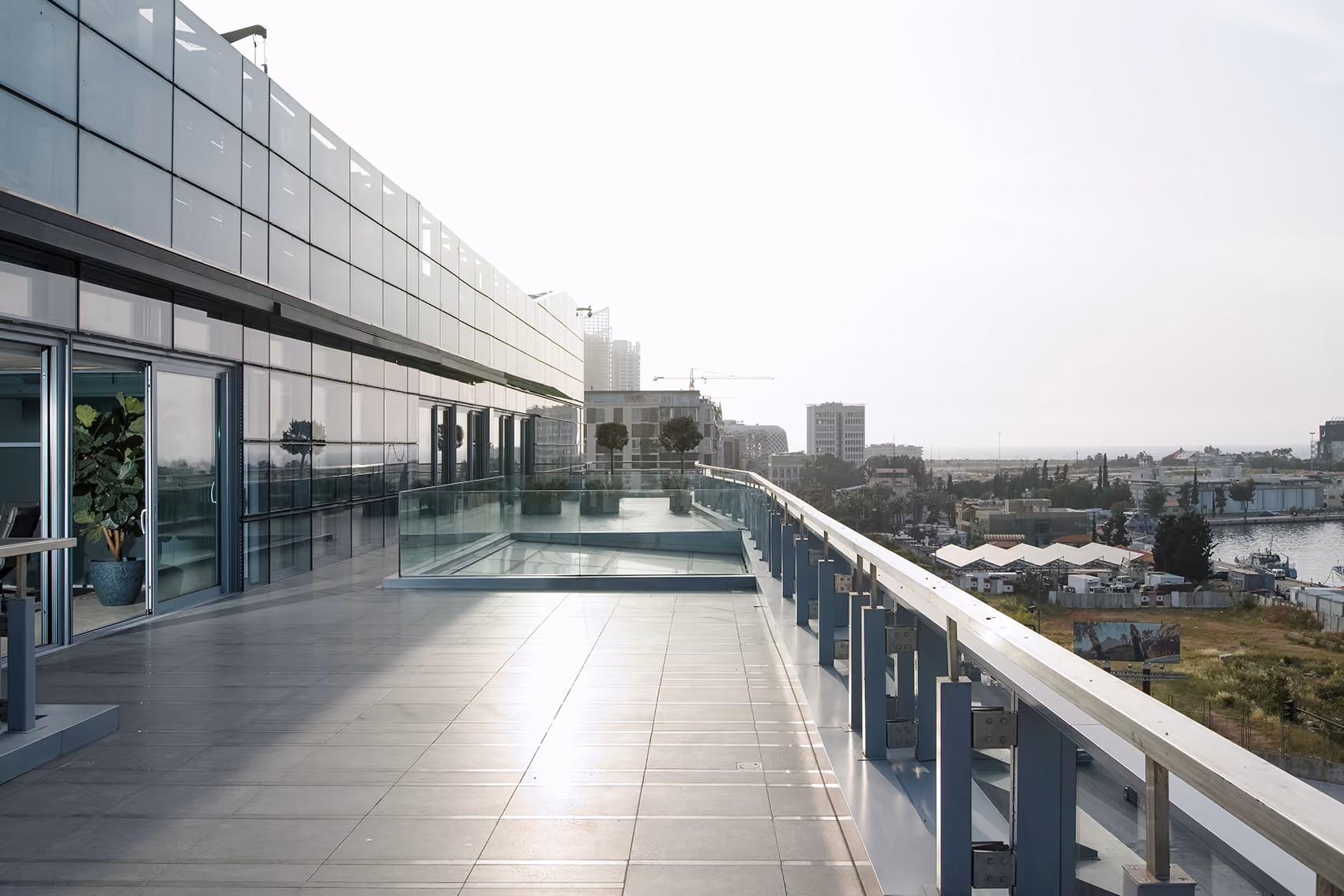 Rooftop terrace of the CMA-CGM Headquarters refurbishment in Beirut, glass balustrade overlooking the port and city skyline at dawn