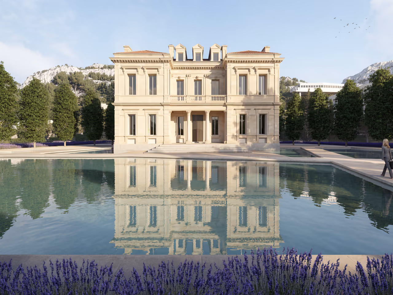 Restored classical limestone facade of the corporate academy in Marseille, mirrored in a reflecting pool bordered by lavender and hillside trees