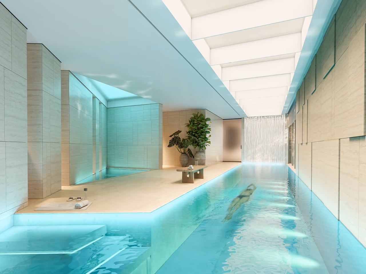 Indoor lap pool at Geode villa in Dubai, a swimmer gliding through turquoise water beside travertine walls and a backlit water feature