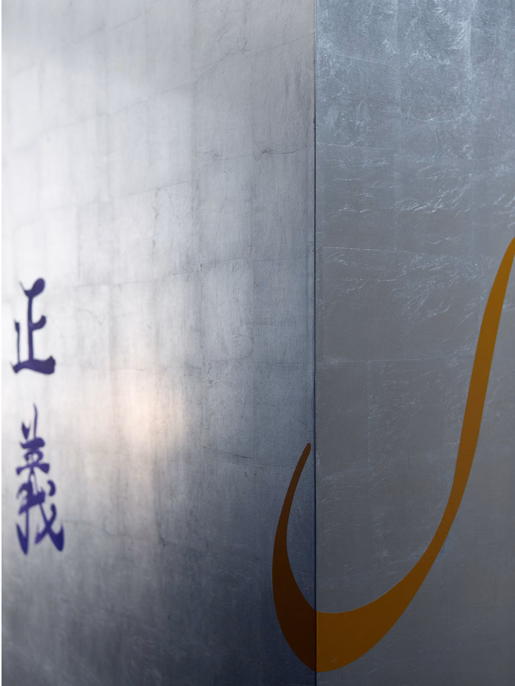 Interior detail at Waqf Foch Office Building in Beirut, brushed metal wall panels with a purple calligraphic character and a curving ochre line accent
