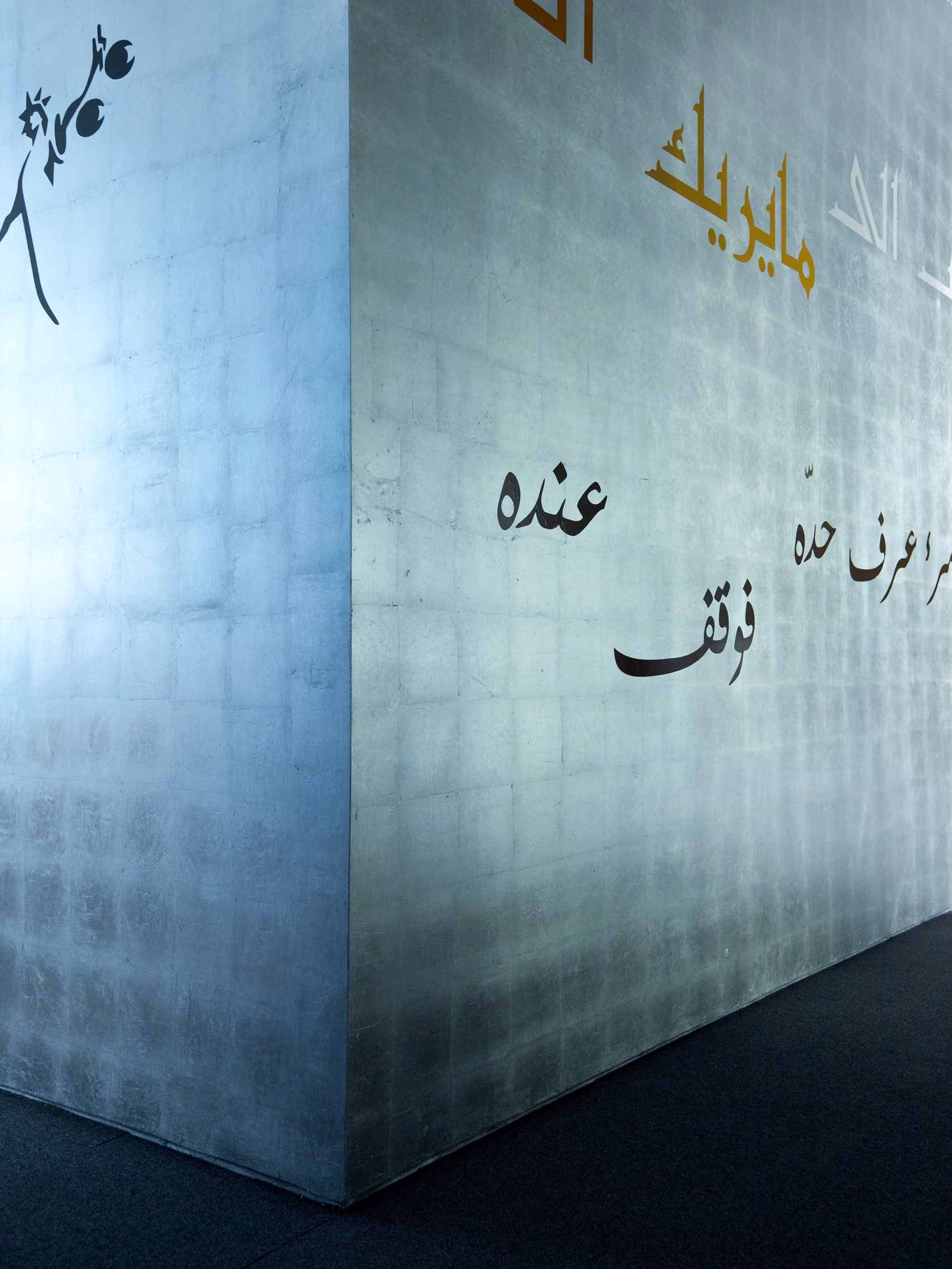Metallic-textured wall corner in the Waqf Foch Office Building lobby in Beirut, engraved with Arabic calligraphy in black and gold