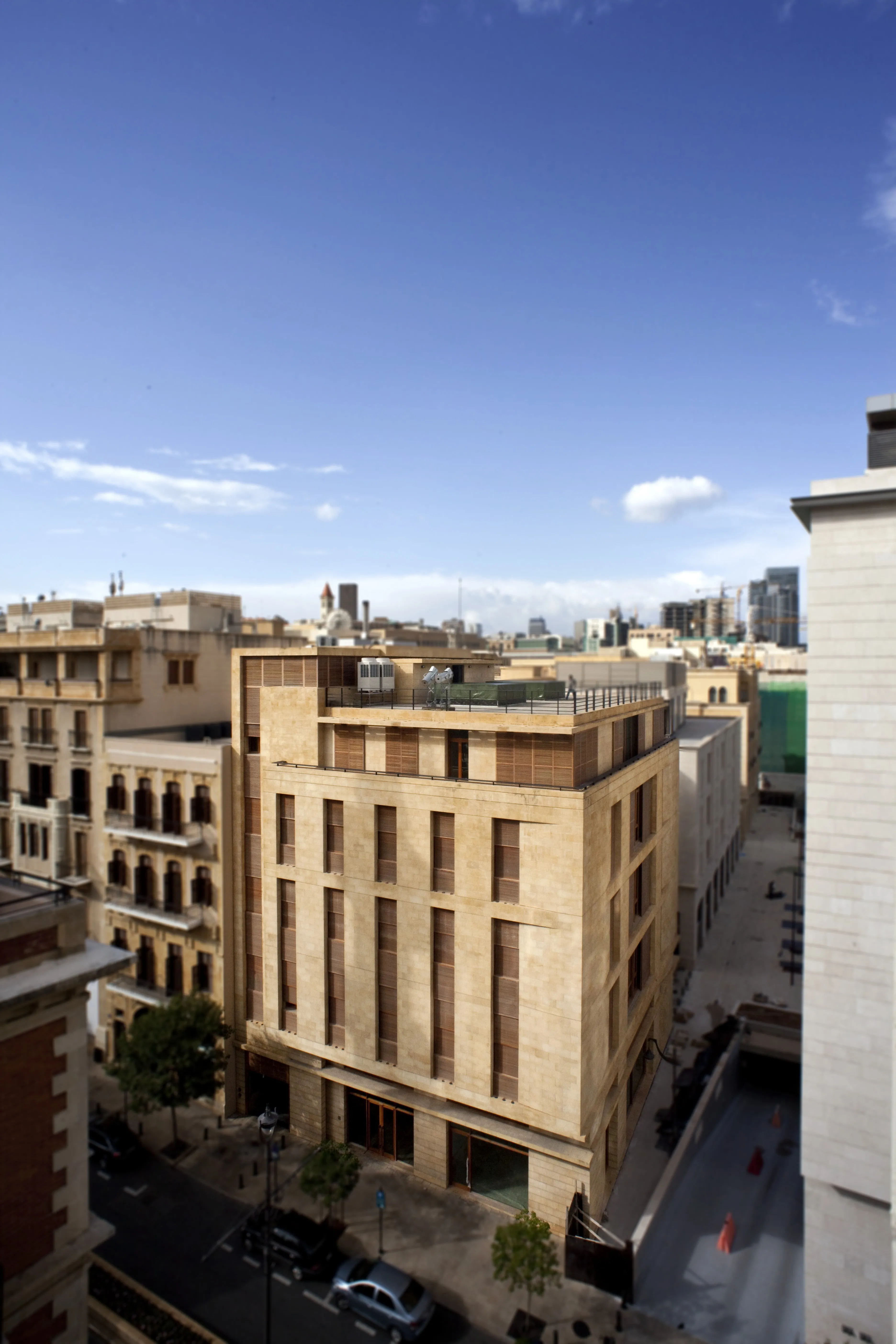 Elevated view of the Waqf Foch Office Building in Beirut, its stone facade with recessed timber shutters standing among heritage buildings and a rooftop terrace