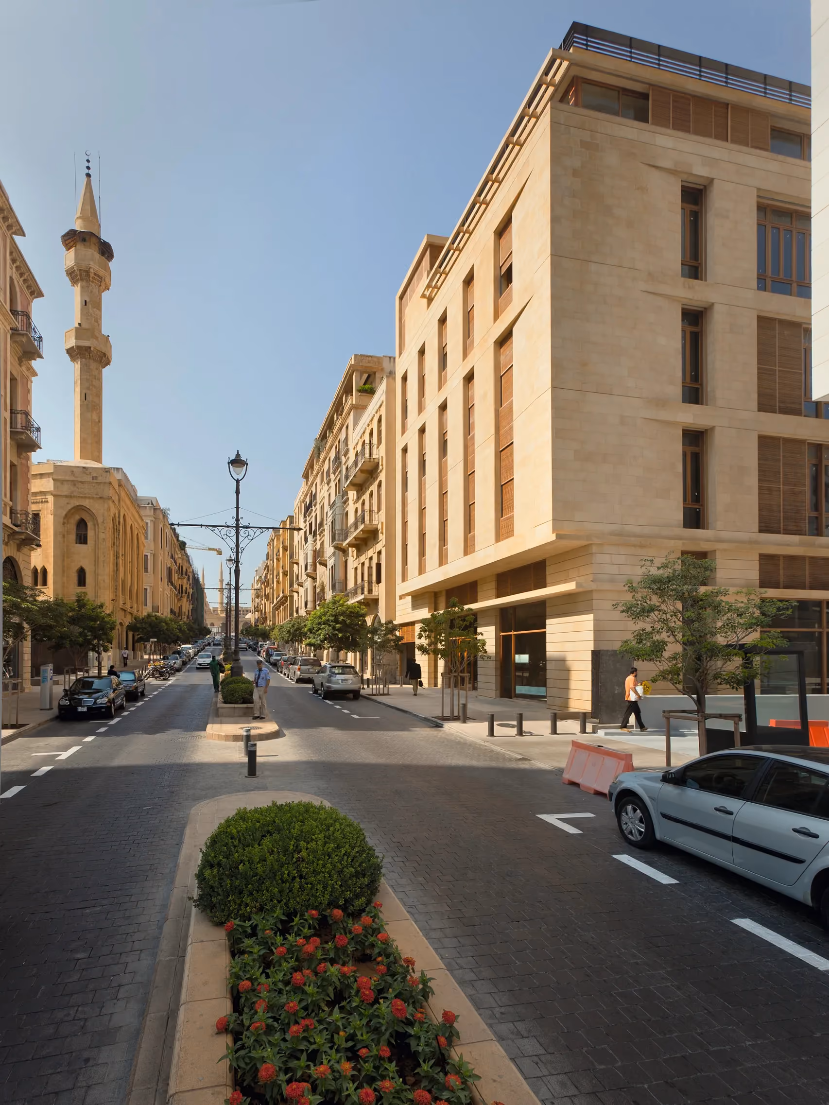 Waqf Foch Office Building in Beirut, sandstone facade with recessed timber-shuttered windows on a tree-lined street near a mosque minaret