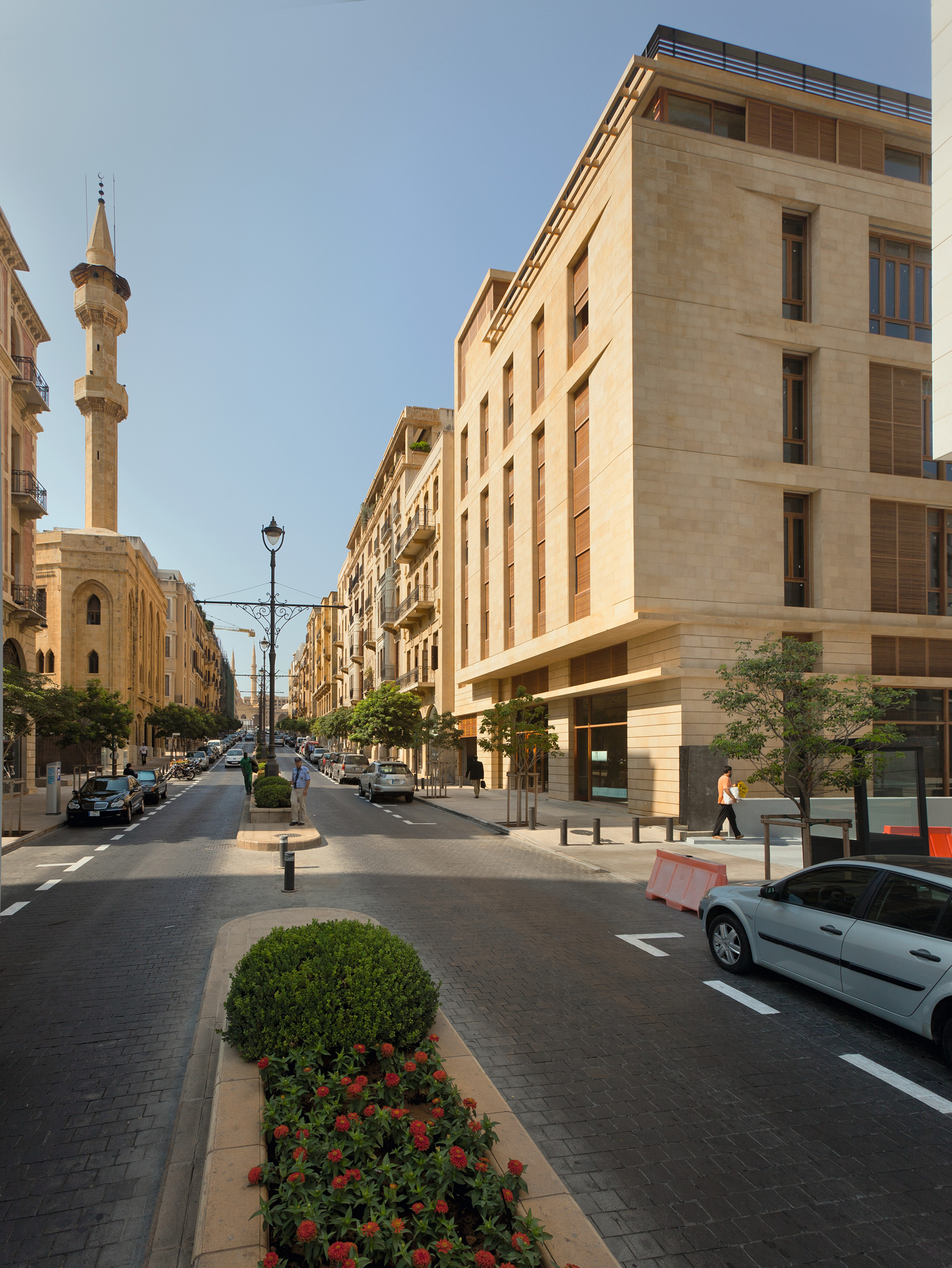 Waqf Foch Office Building in Beirut, sandstone facade with recessed timber-shuttered windows on a tree-lined street near a mosque minaret