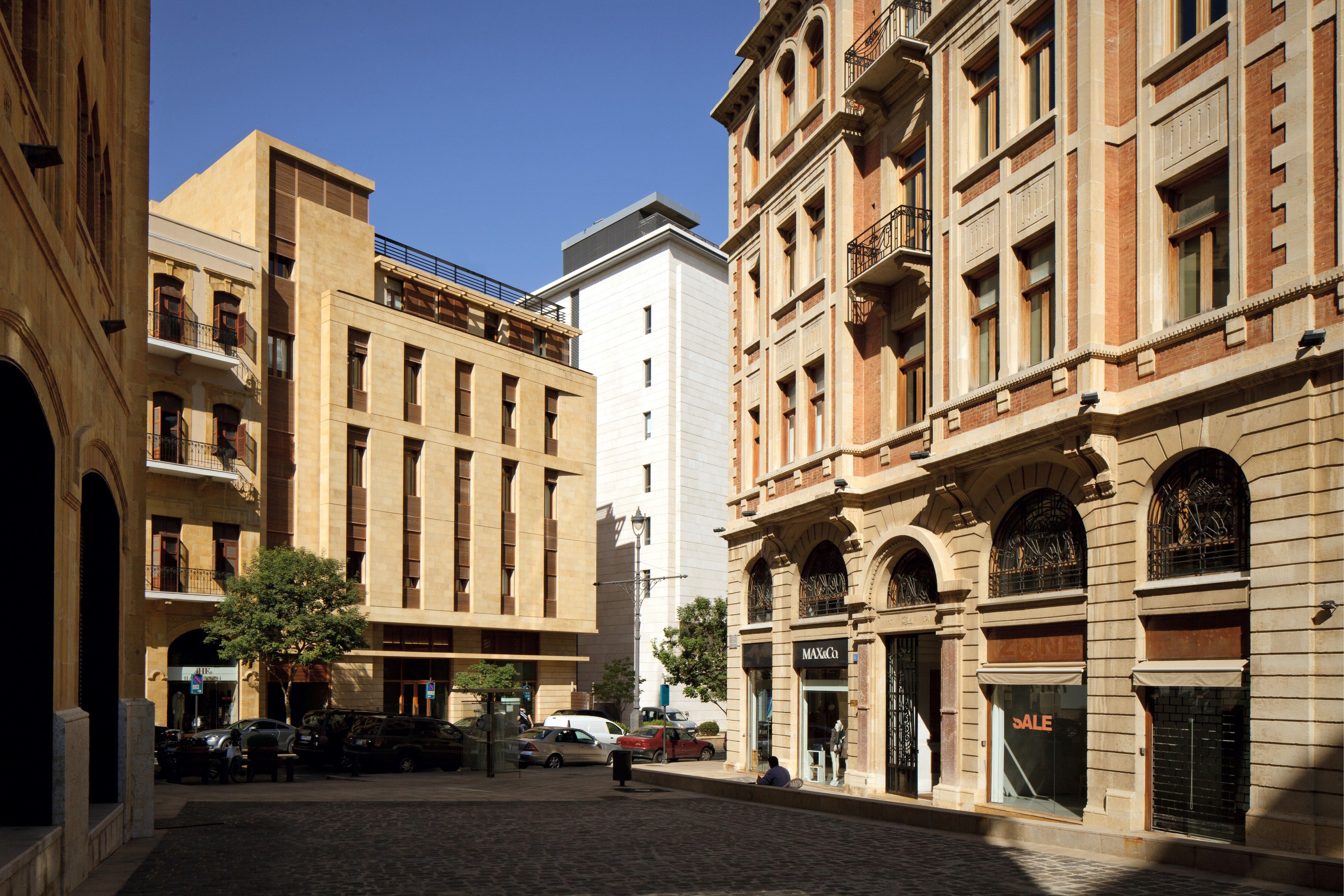 Waqf Foch Office Building by Nabil Gholam Architects, a limestone-clad building with recessed windows rising behind restored heritage facades on a cobbled street in Beirut