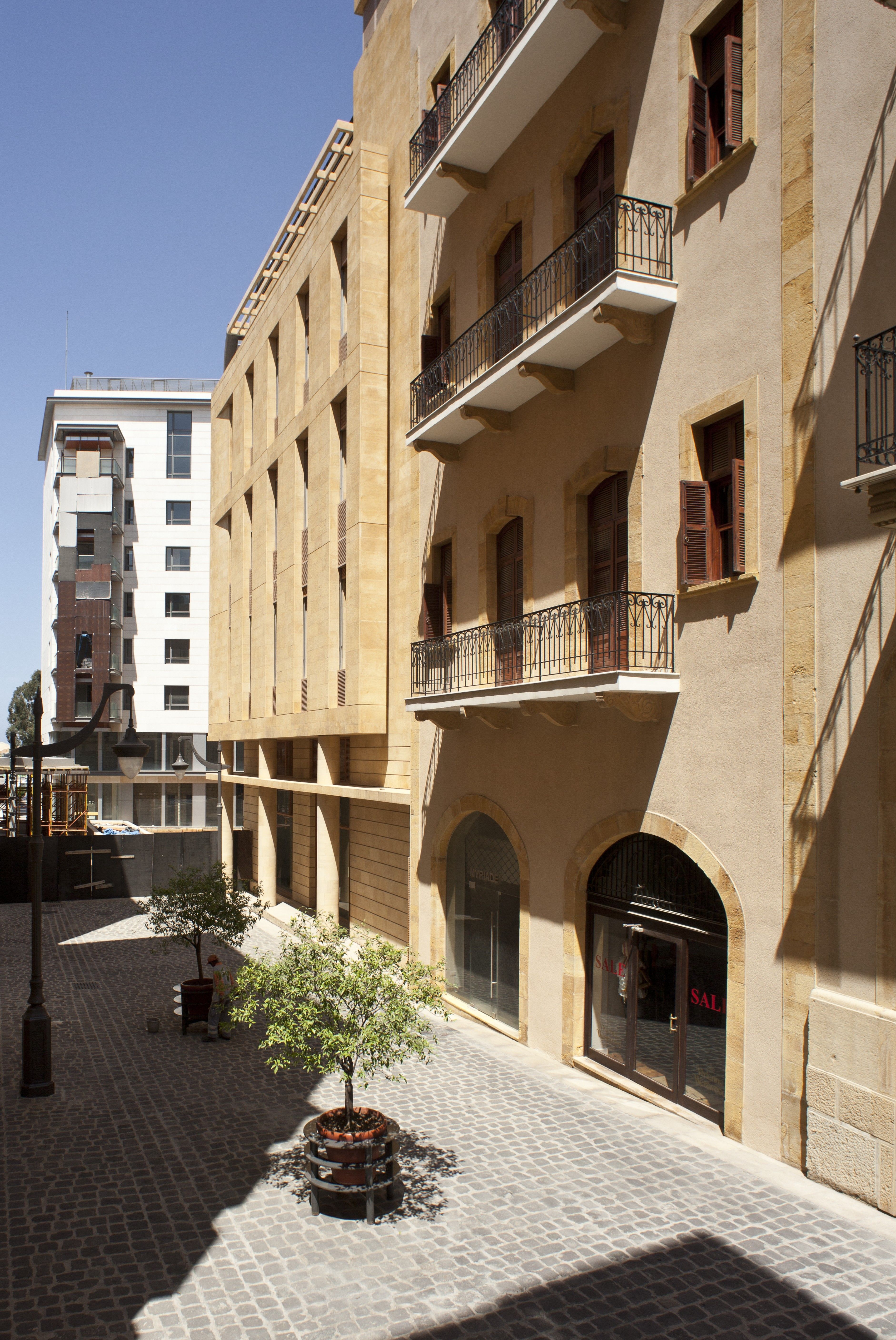 Waqf Foch Office Building in Beirut, stone facade with arched shopfronts, shuttered windows and wrought-iron balconies along a cobbled pedestrian street
