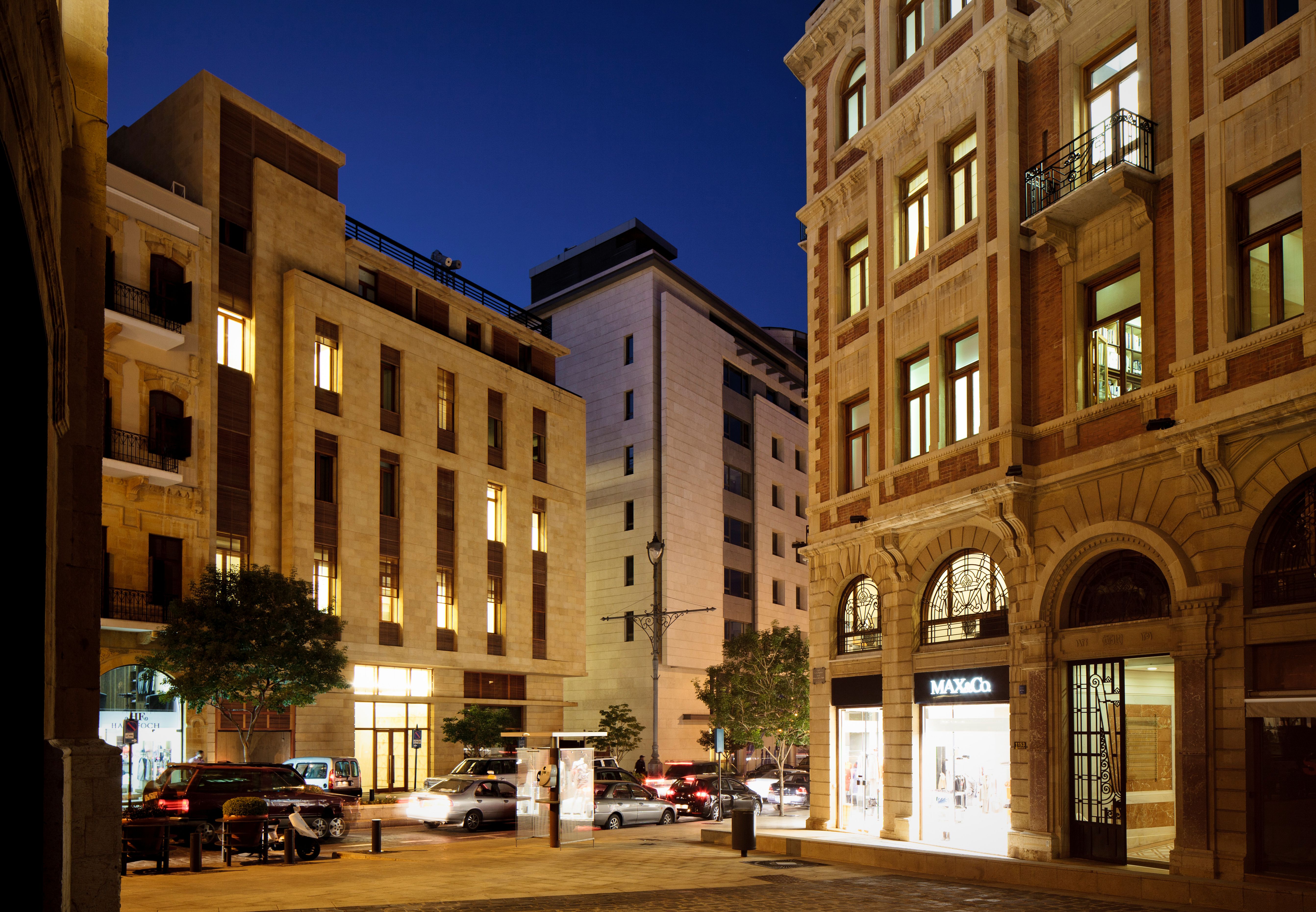 Waqf Foch Office Building in Beirut, illuminated at dusk beside restored heritage facades in the Foch-Allenby district, street level shops and cars below