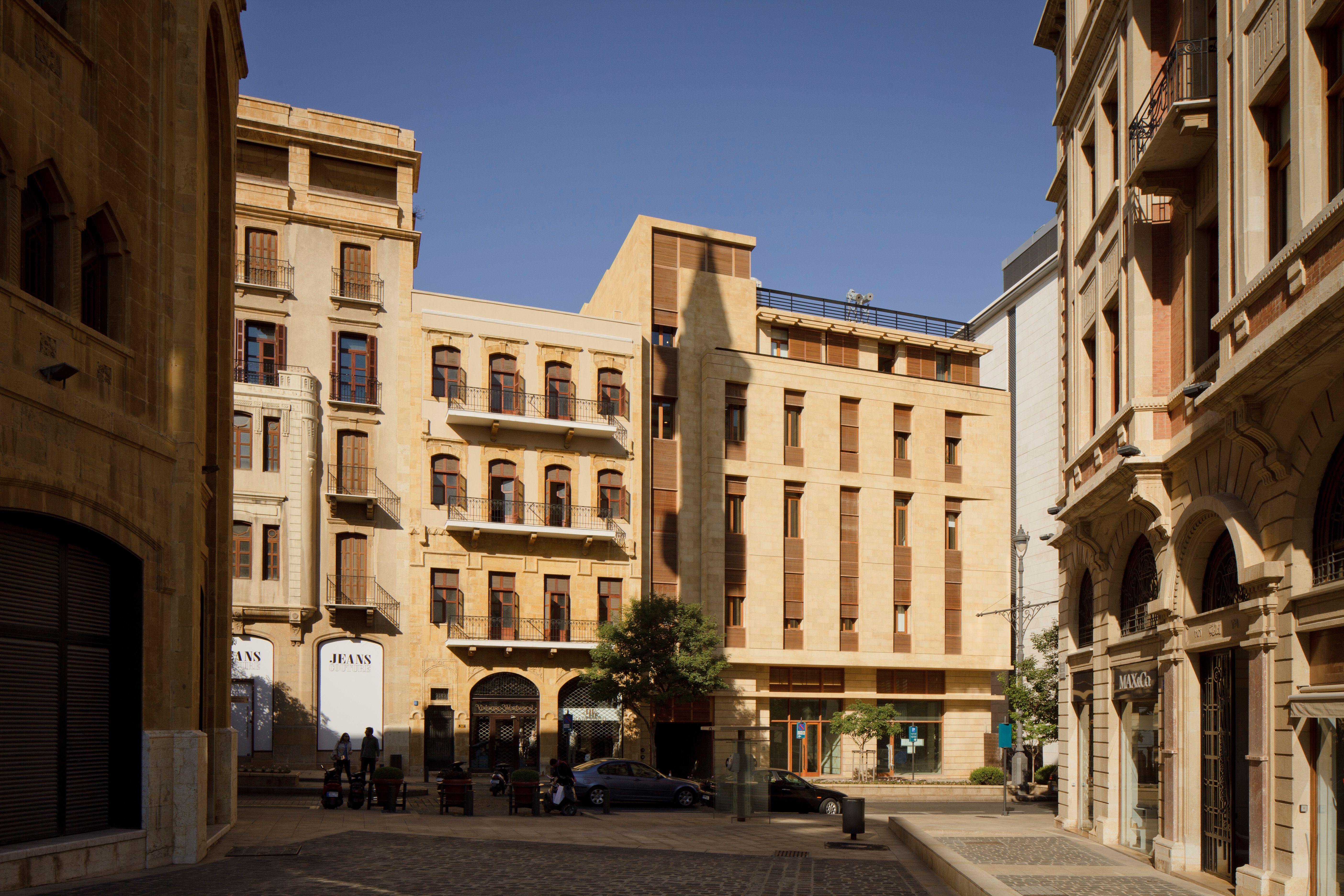 Waqf Foch Office Building in Beirut, stone facade with wooden shutters standing between older heritage buildings along a pedestrian street