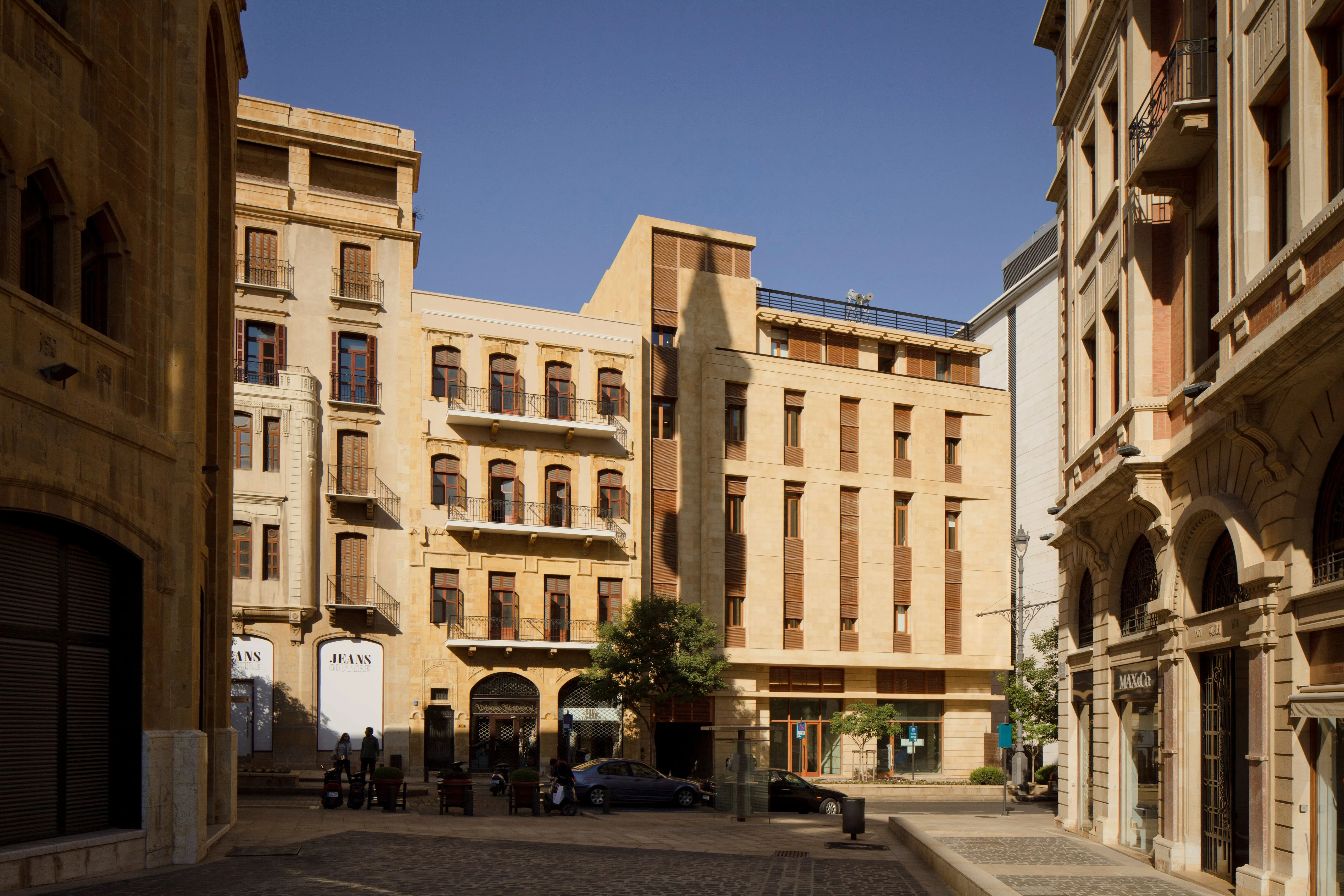 Waqf Foch Office Building in Beirut, stone facade with wooden shutters standing between older heritage buildings along a pedestrian street
