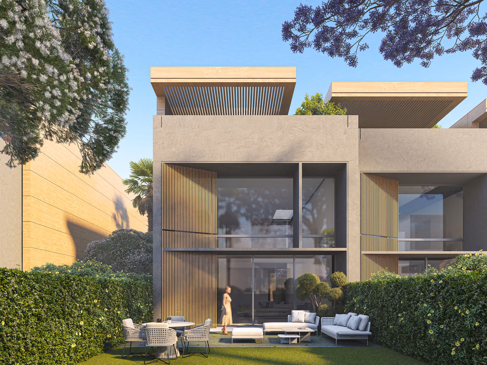 Rear garden view of Beach Club Townhouses in Dubai, a two-storey villa with timber slat screens, projecting wood-clad roof canopies, and a hedge-lined lawn with outdoor seating