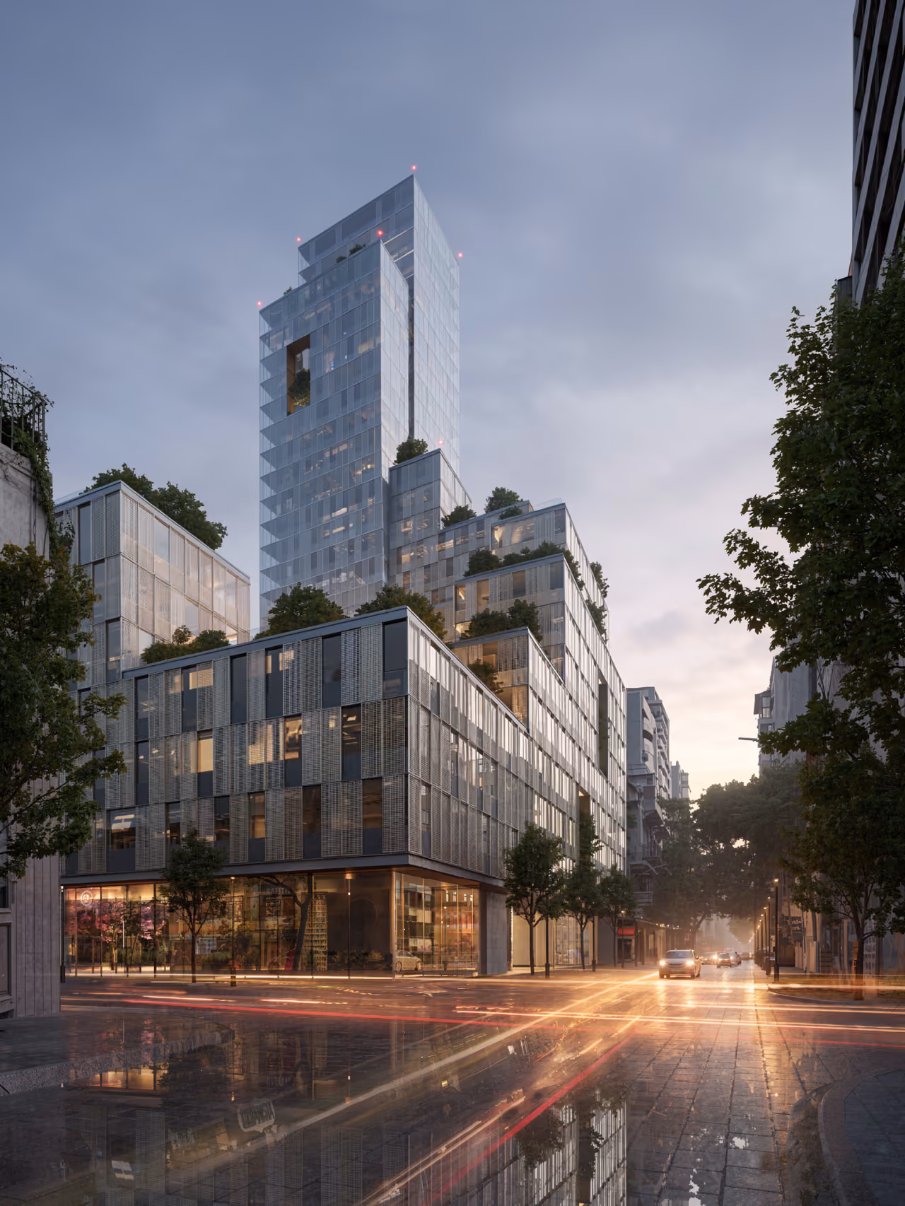 City Campus 01 in Beirut at dusk, a tiered glass tower with terraced greenery rising above a perforated metal-clad podium along a rain-slicked street