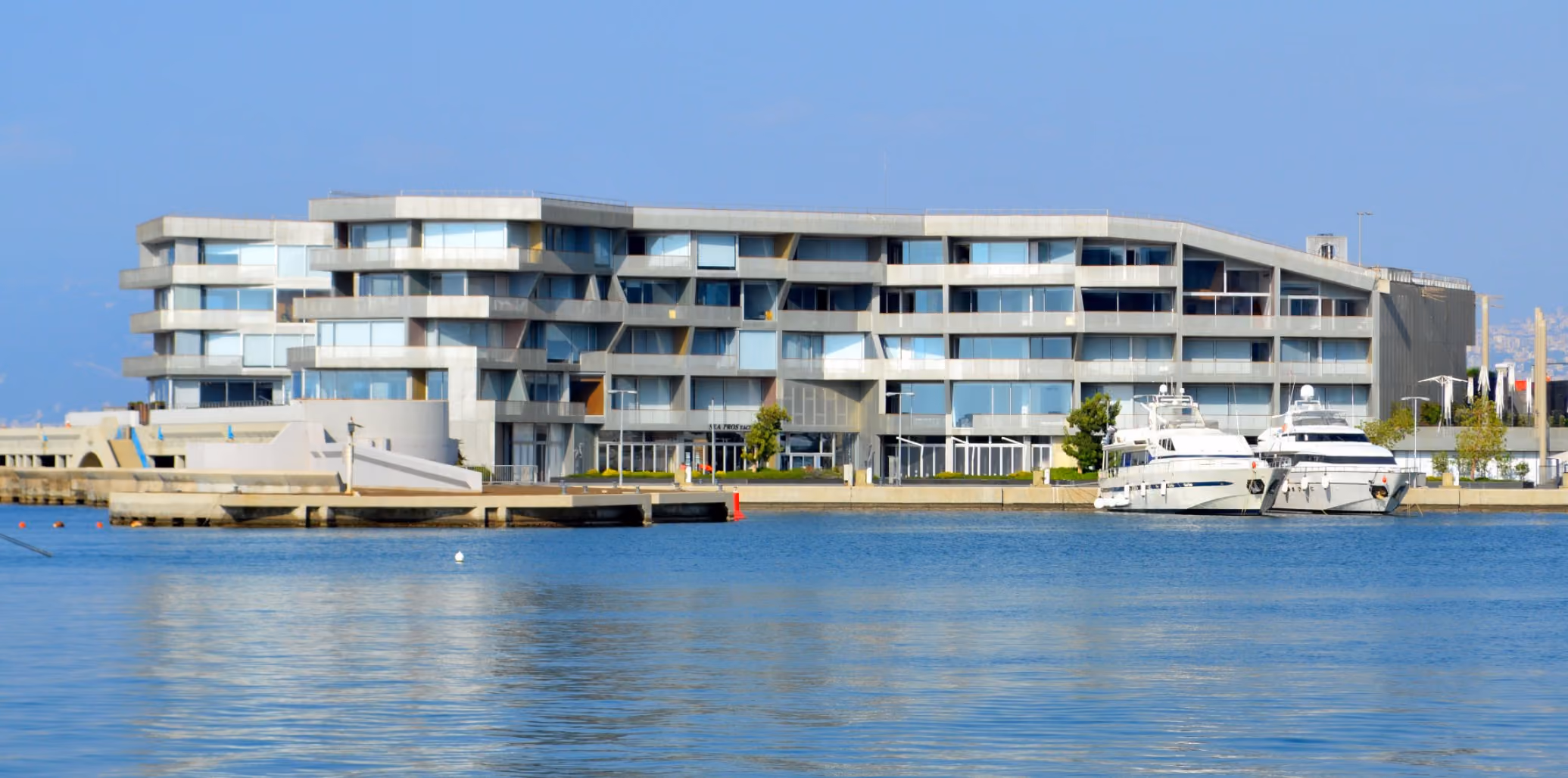 Waterfront view of Beirut Marina & Town Quay, a striated concrete and glass residential building with staggered balconies, yachts moored along the harbour below