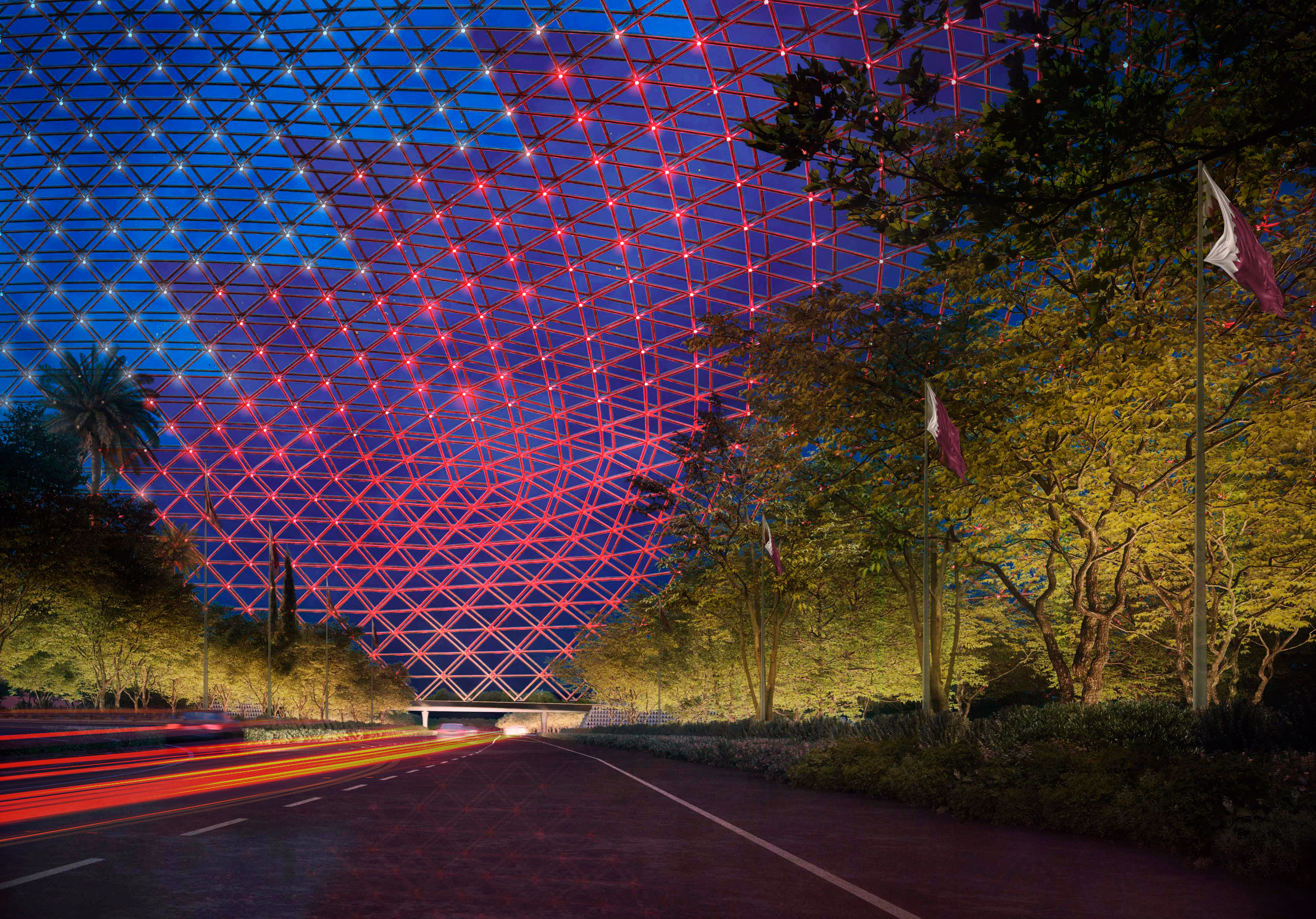 Night view of the Regenerative Dome, a red diagrid canopy glowing over a highway lined with trees and national flags on the Arabian Peninsula