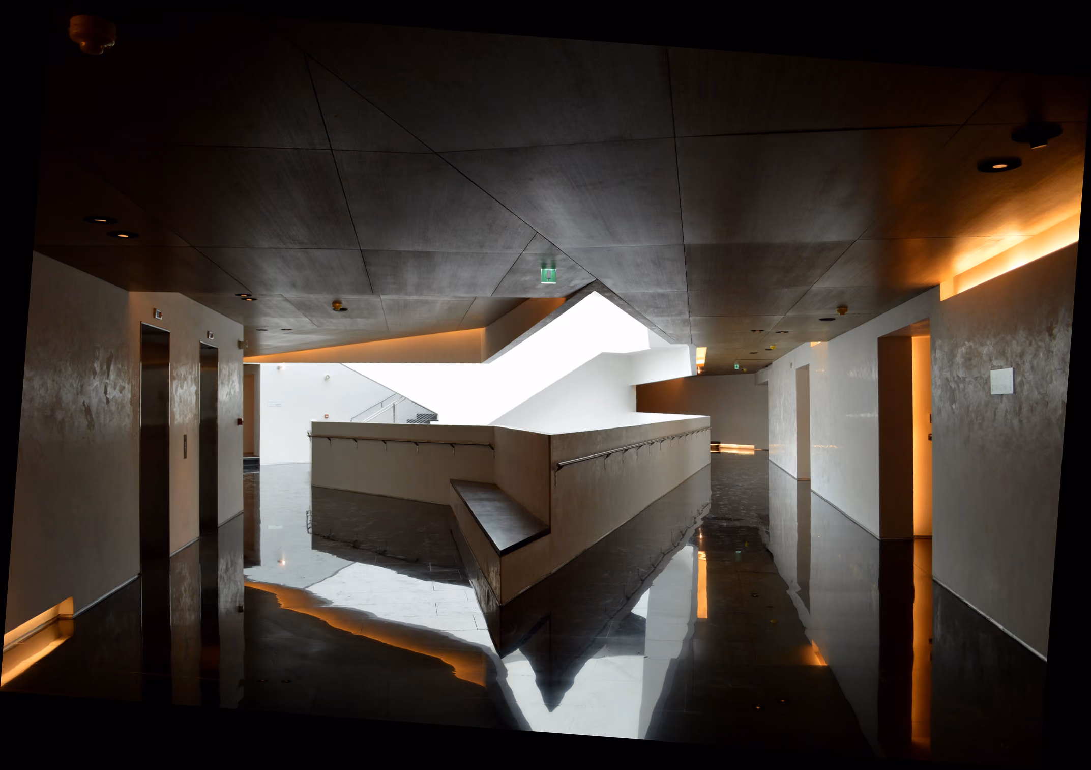 Interior corridor at Beirut Marina & Town Quay with polished dark floors reflecting a glowing skylight and angular white balustrade