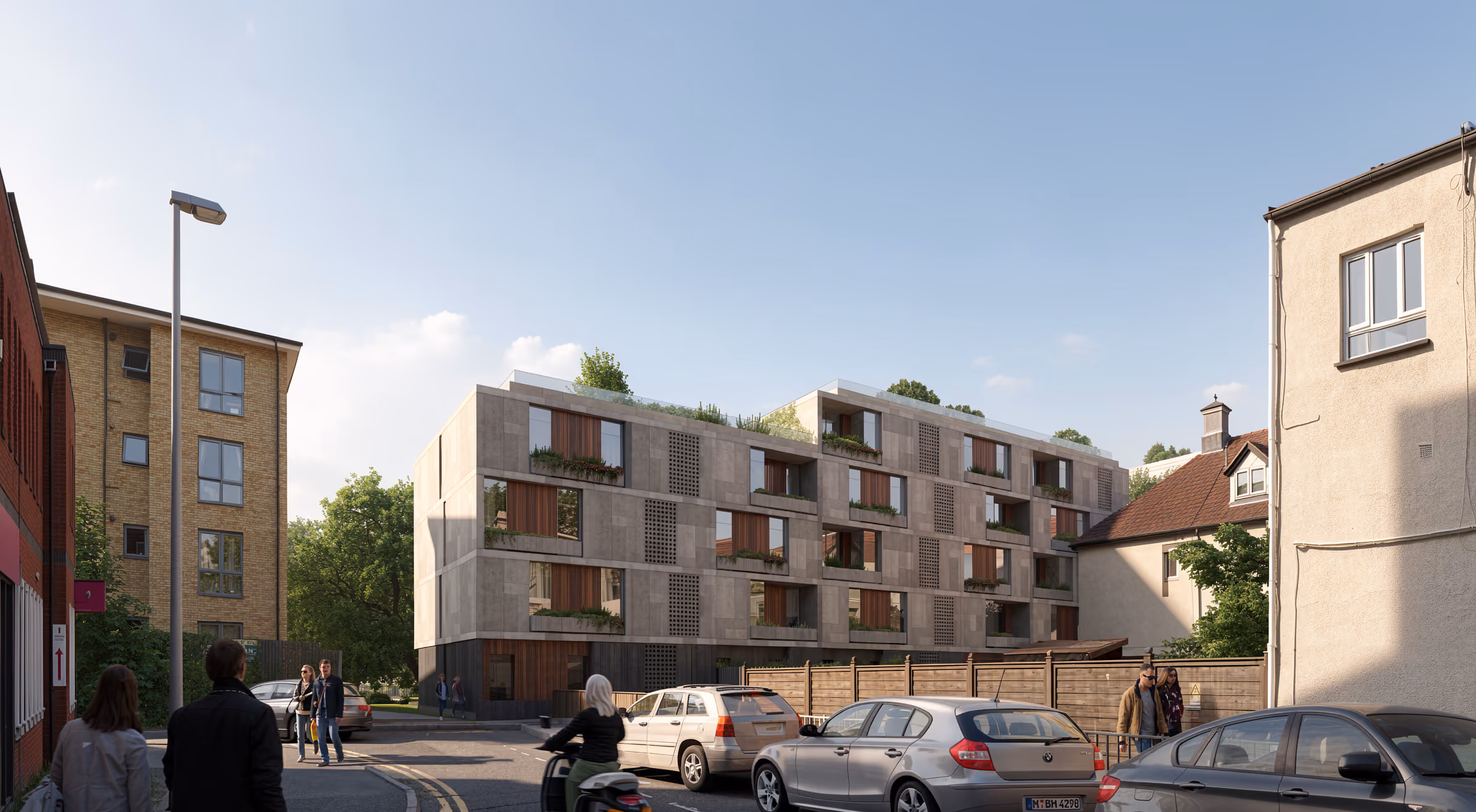 Street-level view of Parkway Road in Chelmsford, a mid-rise residential building with a stone-toned facade, timber accents and planted terraces beside a residential street