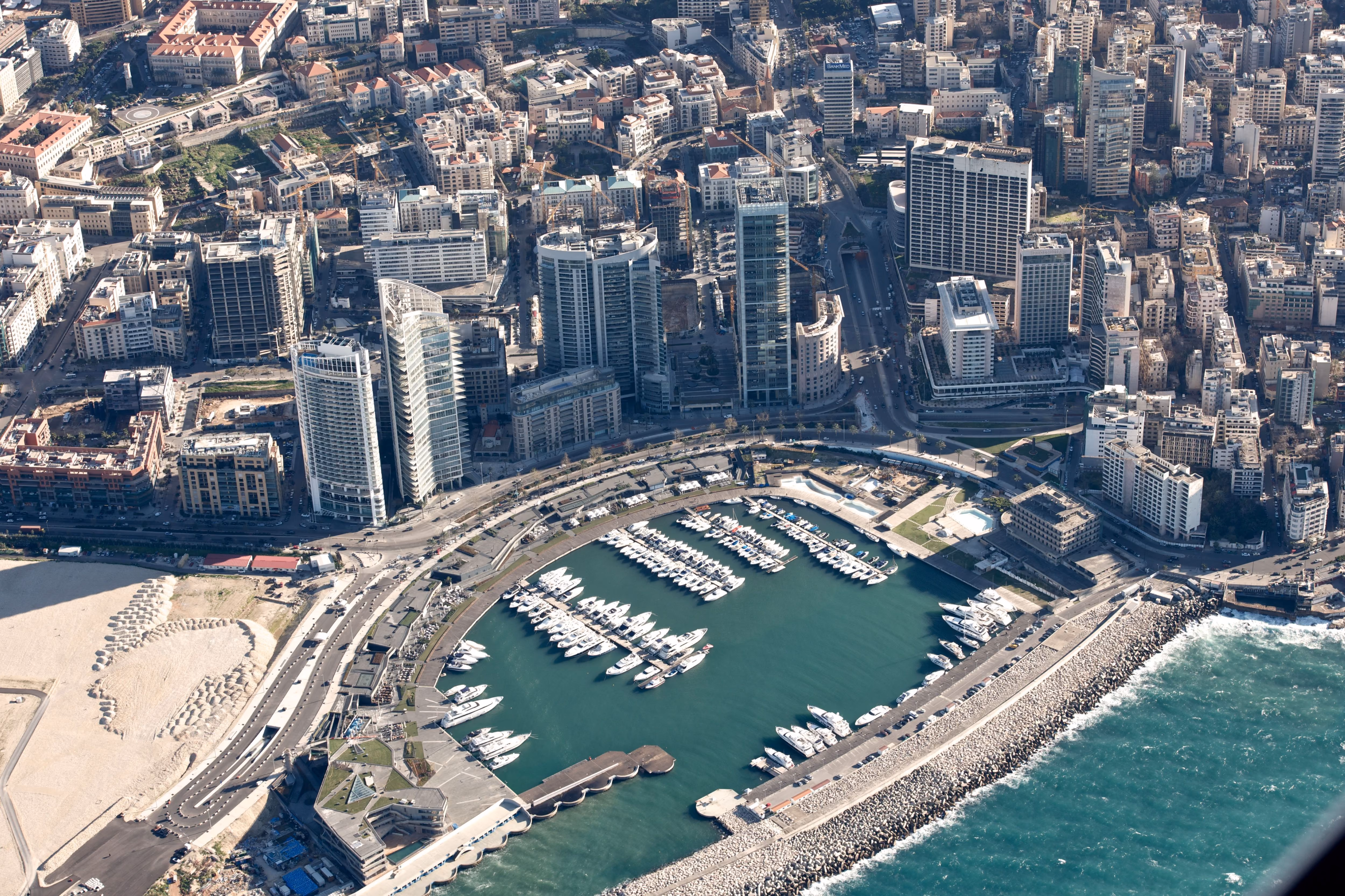 Aerial view of Beirut Marina & Town Quay, curved harbour packed with yachts framed by high-rise towers and the dense Beirut cityscape beyond