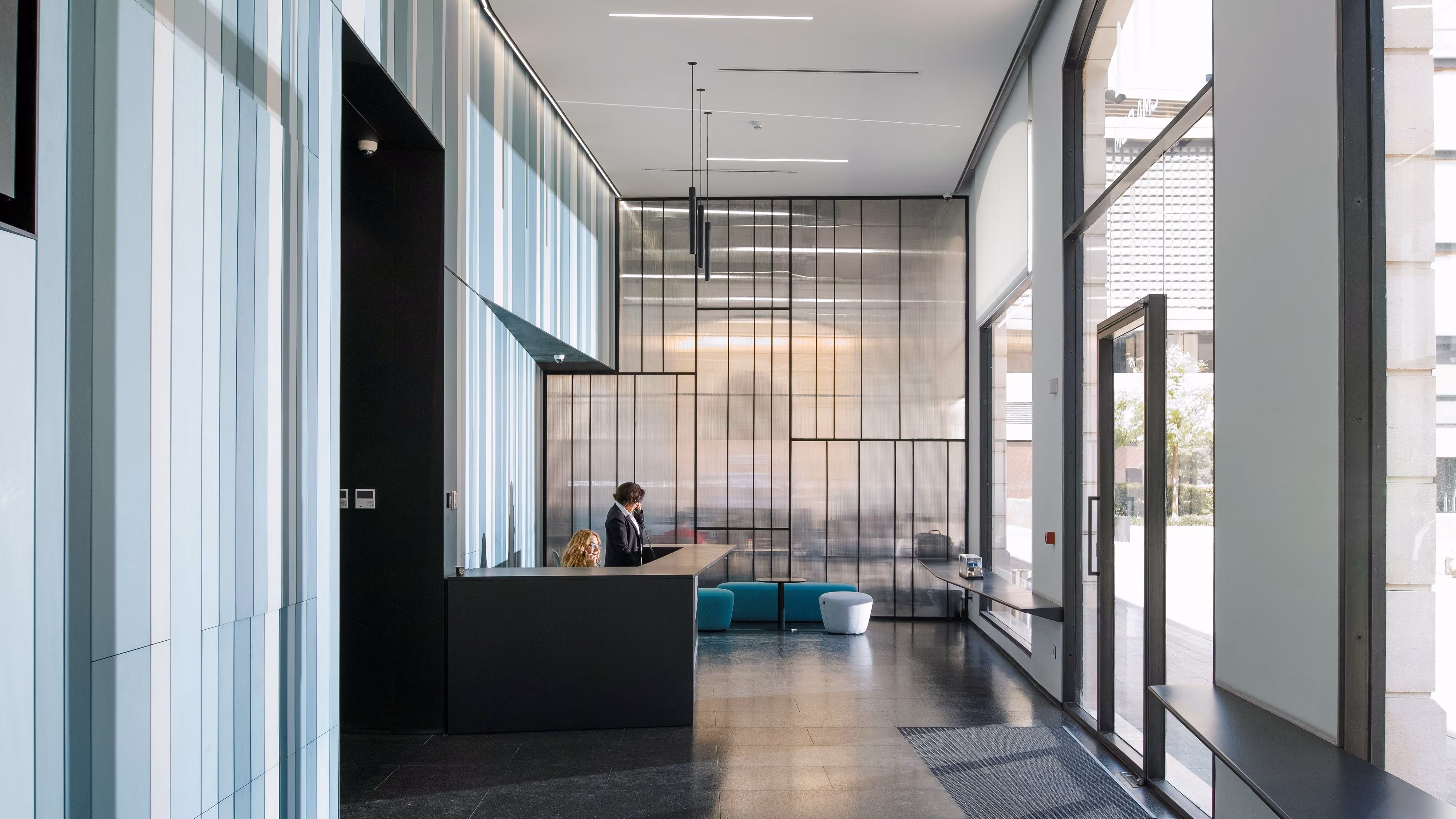 Lot 114 lobby by Nabil Gholam Architects in Beirut, Lebanon, featuring a metal-framed glass partition, dark reception desk and floor-to-ceiling glazing to the plaza