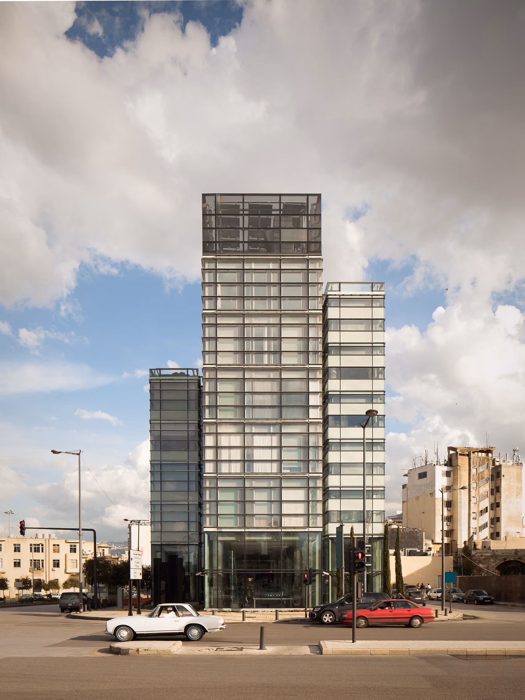 CMA-CGM Headquarters Refurbishment in Beirut, a stepped glass tower of varying heights rising above intersecting streets with traffic and older low-rise buildings nearby