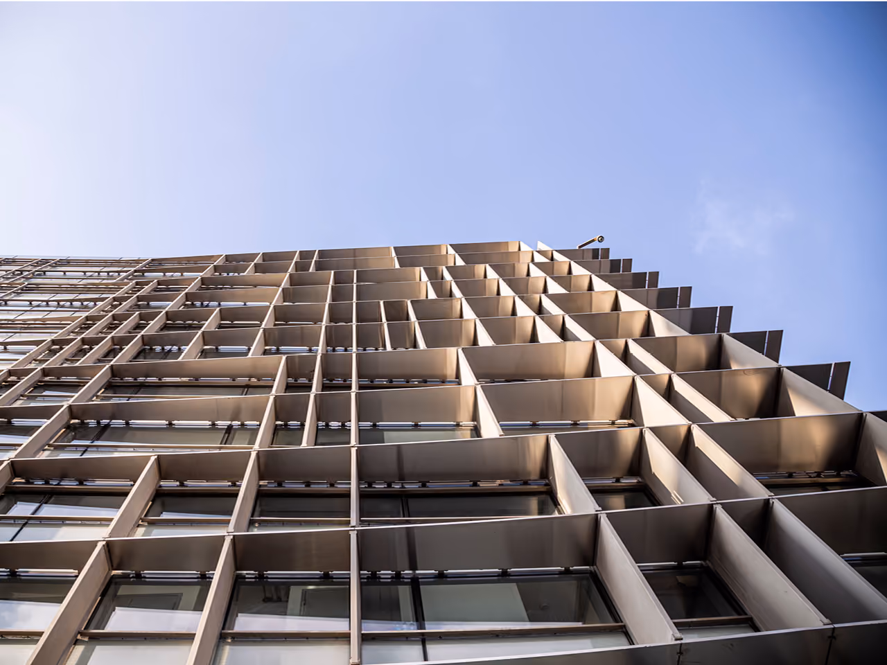 Upward view of the CMA-CGM Headquarters refurbishment in Beirut, a grid of projecting metal fins climbing the facade against a clear sky