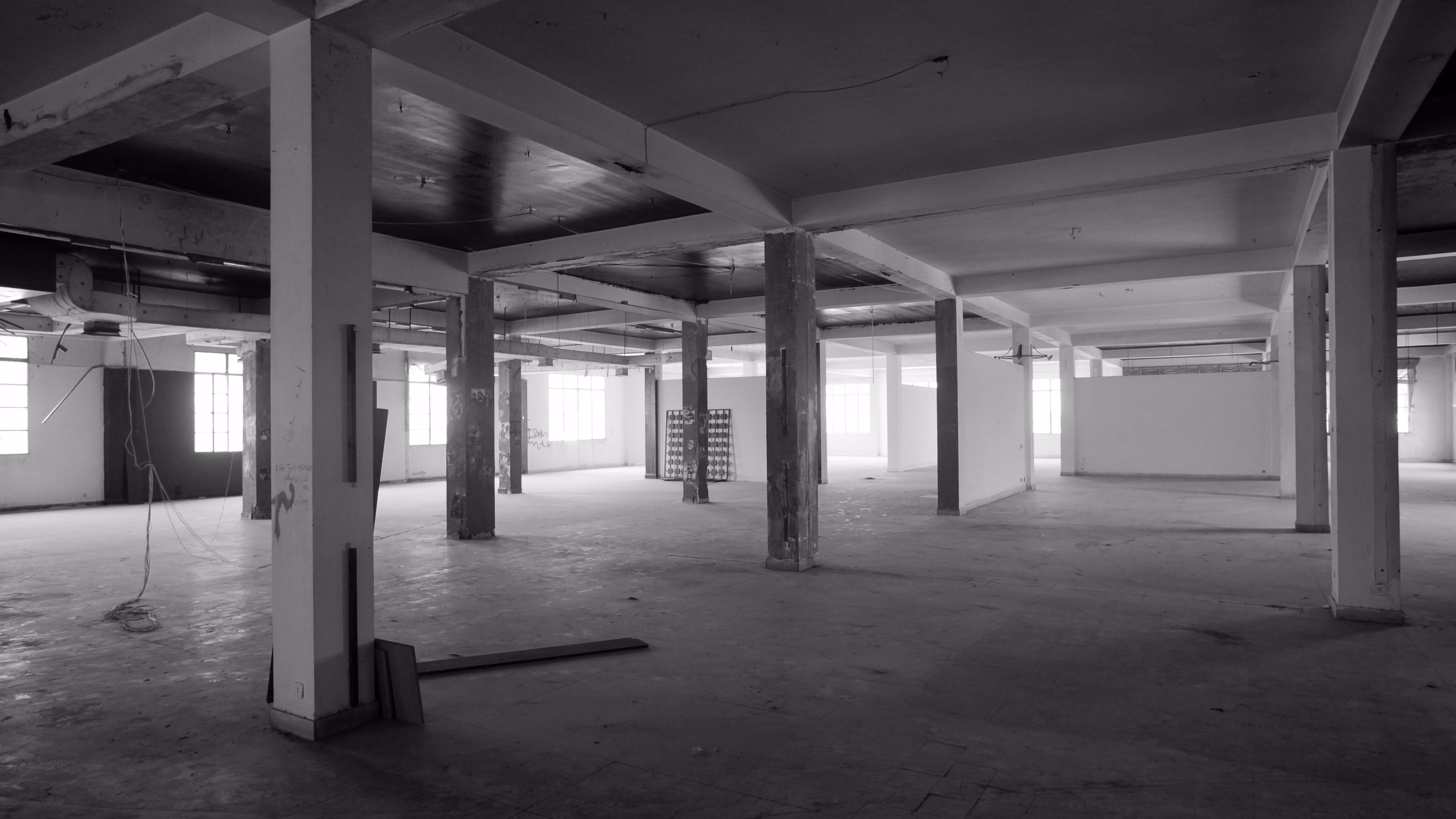 Black and white photograph of the raw industrial shell before renovation of ngª Office in Beirut, showing a grid of concrete columns in an empty open floor