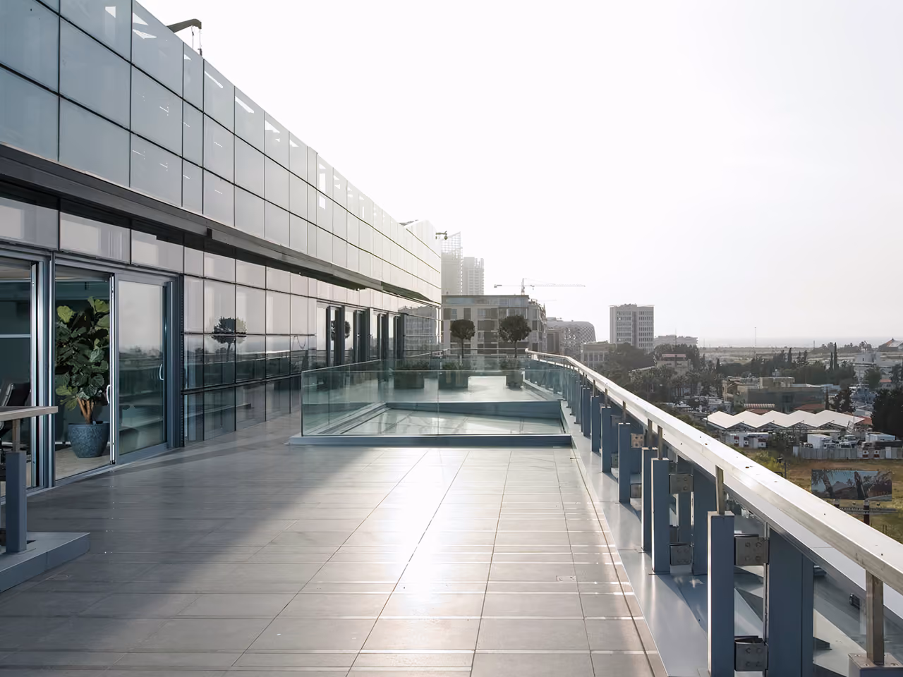 Rooftop terrace of the CMA-CGM Headquarters refurbishment in Beirut, glass balustrades and potted greenery overlooking the city skyline at dawn
