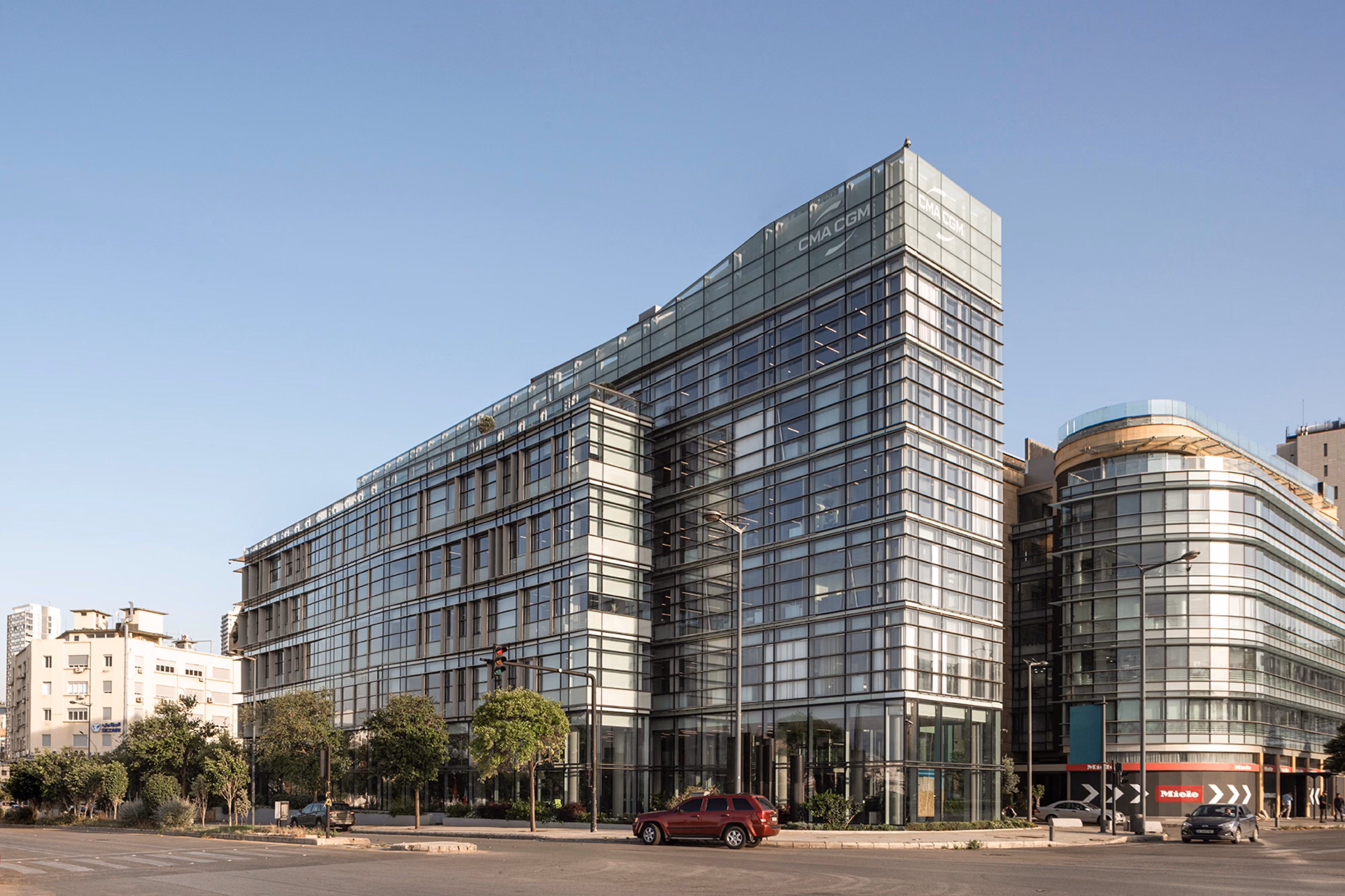 CMA-CGM Headquarters Refurbishment by Nabil Gholam Architects, a sloped glass-clad office tower with angular tapered roofline on a busy Beirut, Lebanon street corner
