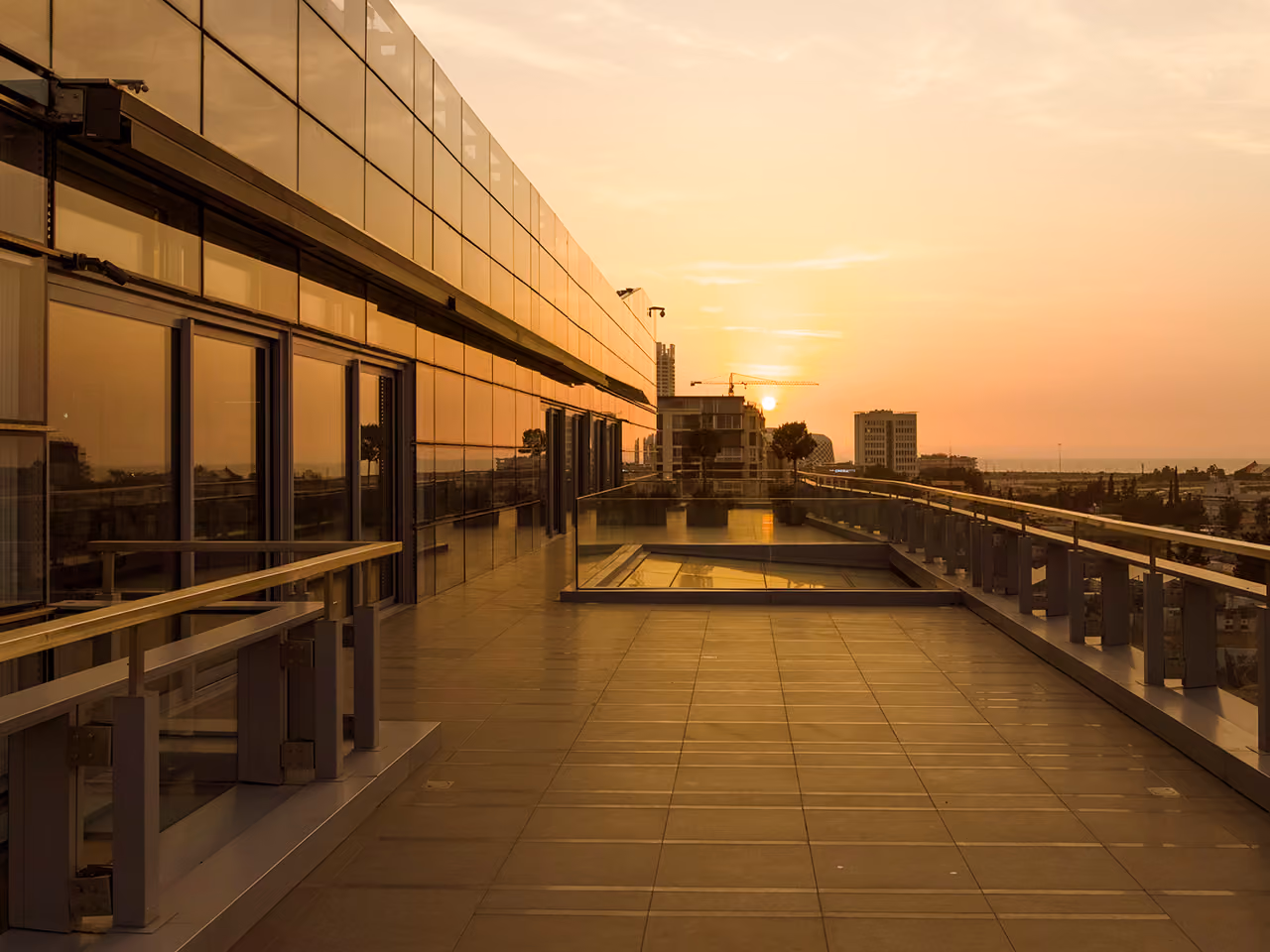 Rooftop terrace of the CMA-CGM Headquarters in Beirut at sunset, glass balustrades and skylight overlooking the city skyline and a distant crane