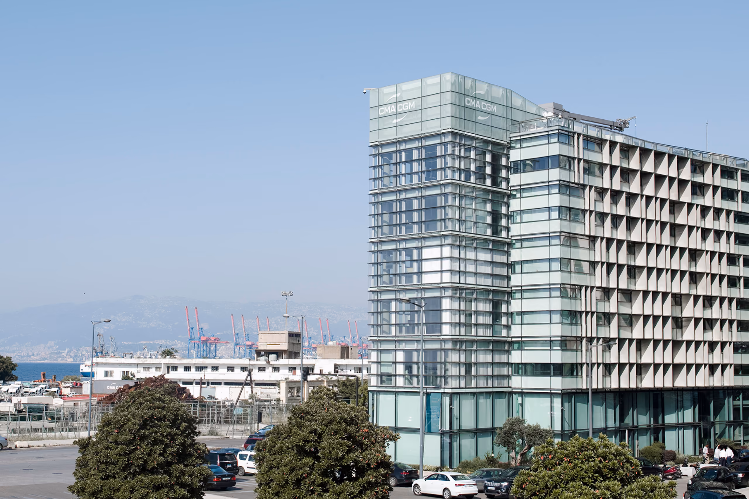 CMA-CGM Headquarters in Beirut, glazed tower with perforated concrete screen facade overlooking the port cranes and sea beyond