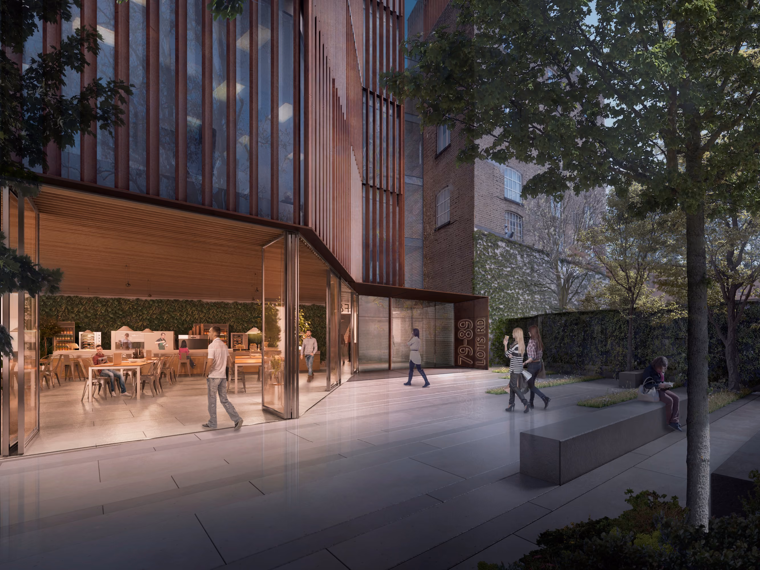 Ground-level cafe and entrance at 78-89 Lots Road in Chelsea, London, with a timber-slatted facade, glazed pavilion and landscaped paved courtyard at dusk