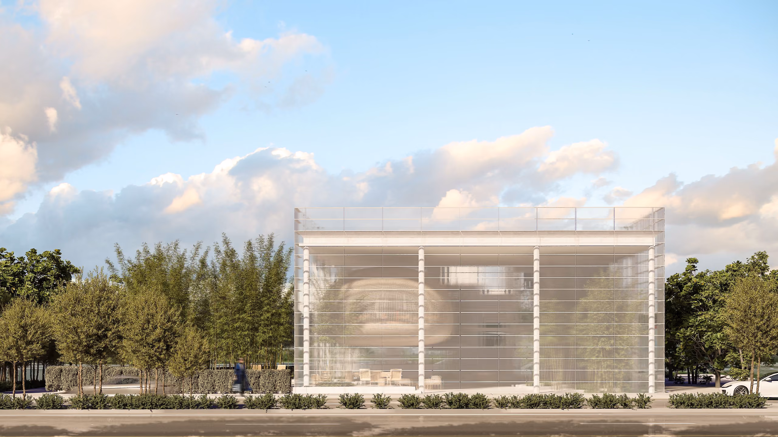 Glass-walled pavilion of Art Hub in Beirut, a colonnaded facade with a woven cocoon-shaped pod visible inside, fronted by bamboo and hedges along the street