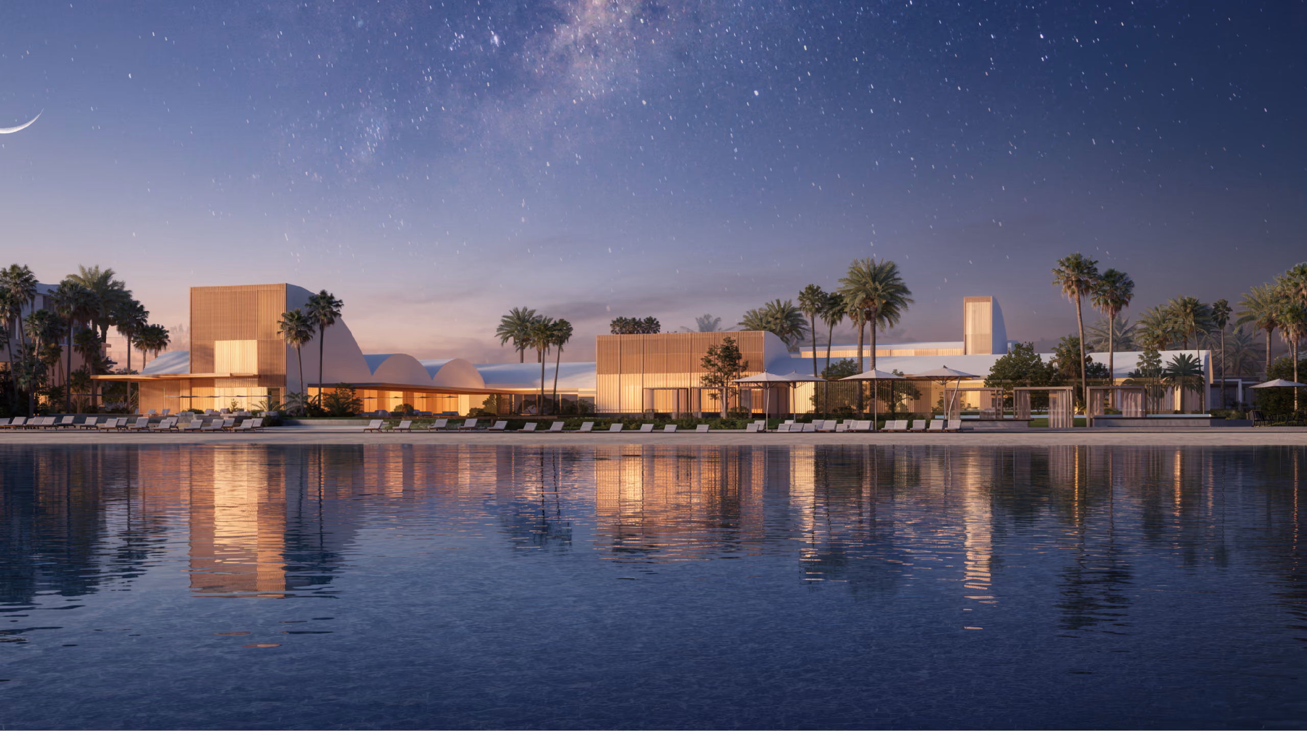 Serenity Beach Club in Dubai at twilight, timber-clad vaulted pavilions lit warmly along the shoreline, palm trees and loungers reflected in calm water under a starry sky