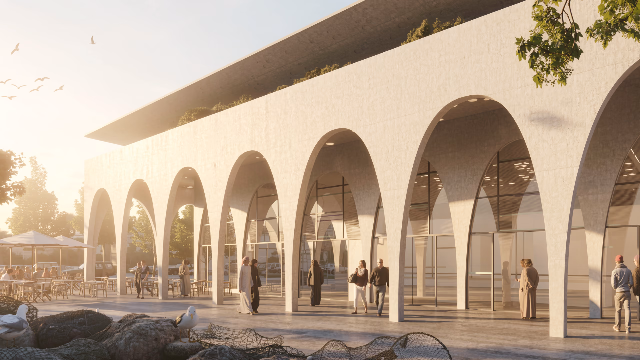 Arched stone colonnade of the Fish Market, pedestrians strolling beneath repeated concrete arches shading a glazed facade at sunset
