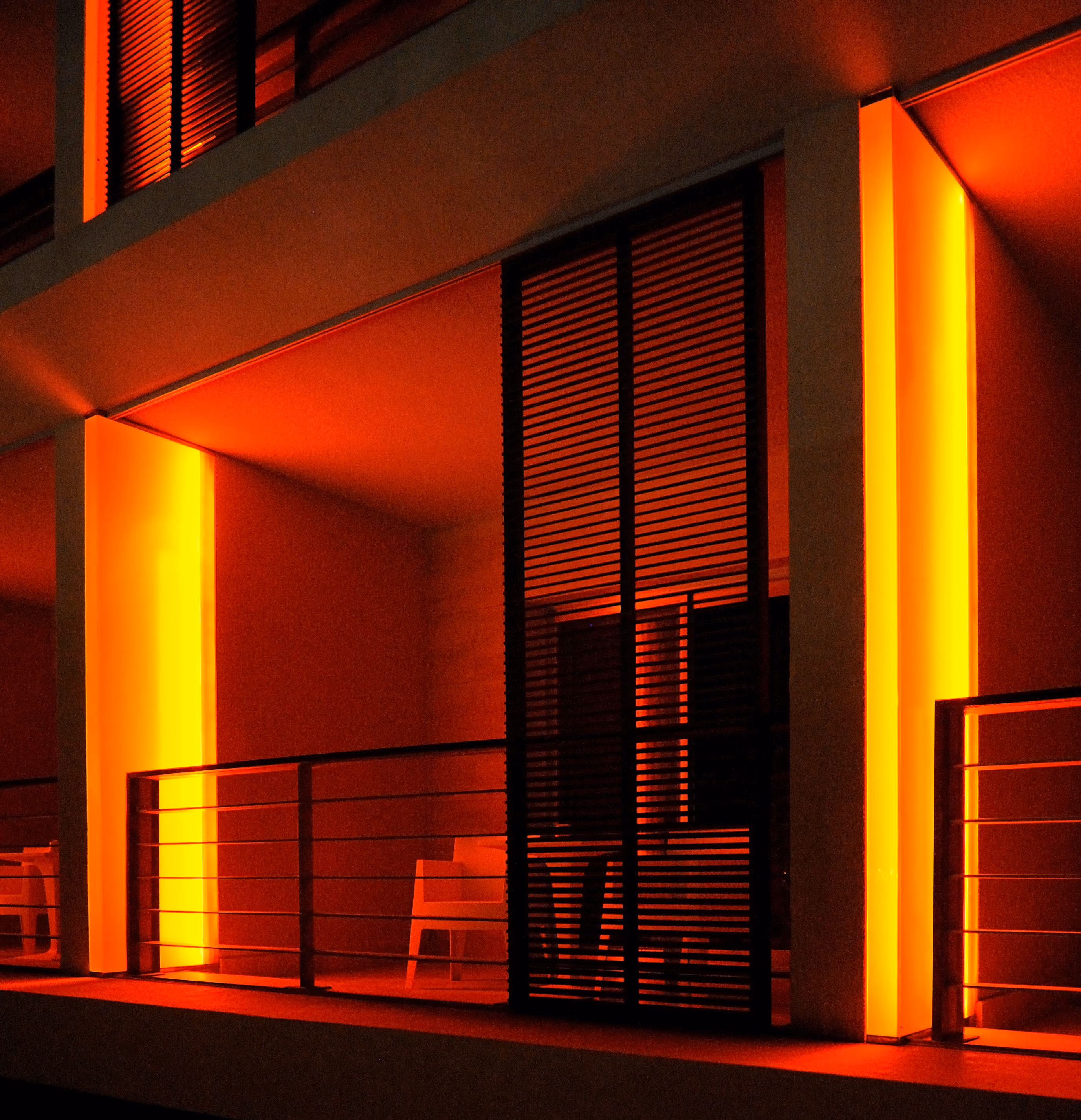 Balcony at the Kempinski Hotel in Aqaba glowing with warm orange uplighting, louvred timber shutters and slim balustrades at night