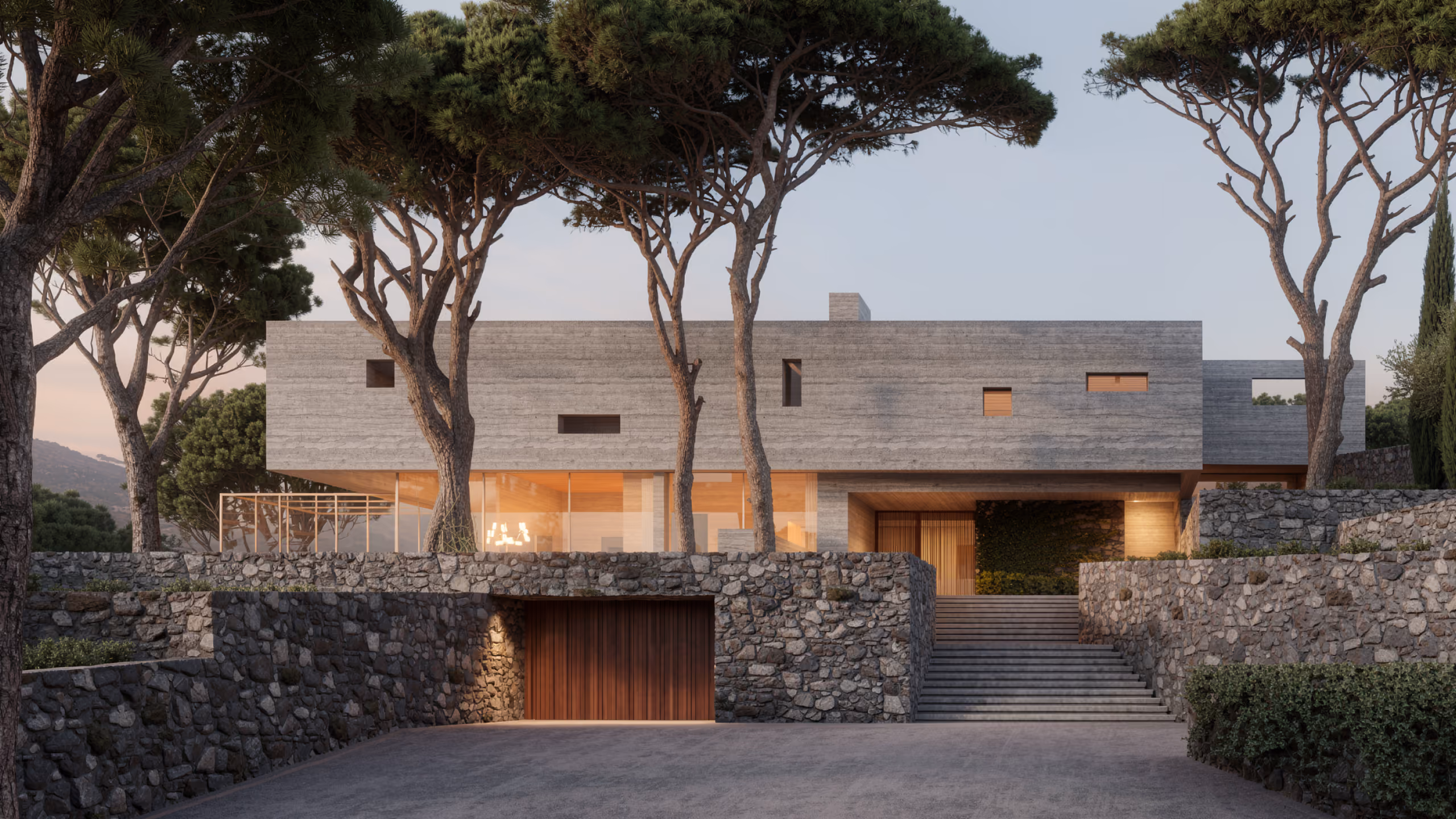 YM House in Deir el Qamar, a concrete volume nestled among pine trees behind stone retaining walls, with a stepped stone staircase leading to a glowing entrance