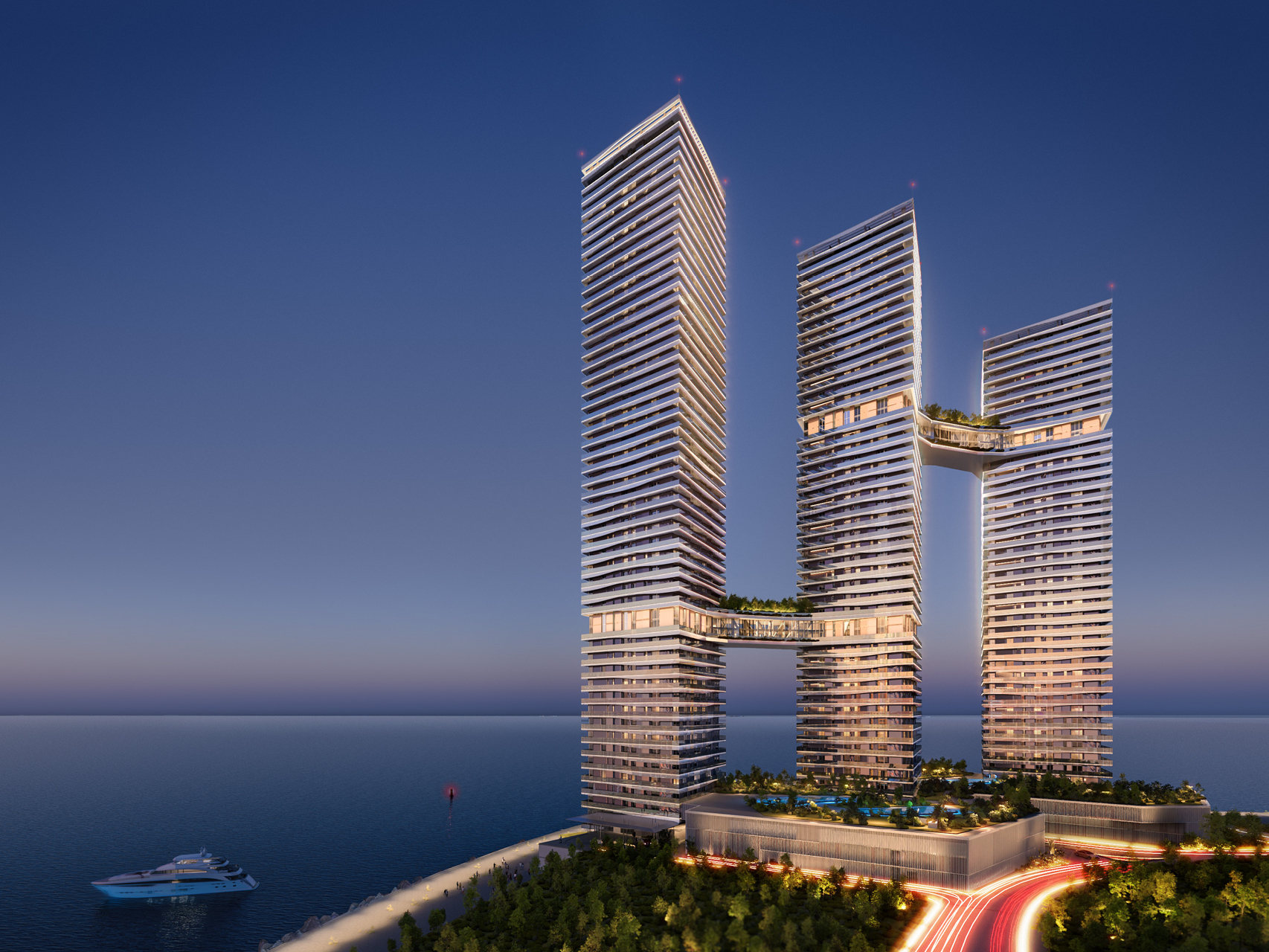 Trilliant in Dubai, three faceted high-rise towers linked by sky bridges, illuminated at dusk above a coastal promenade with a yacht offshore