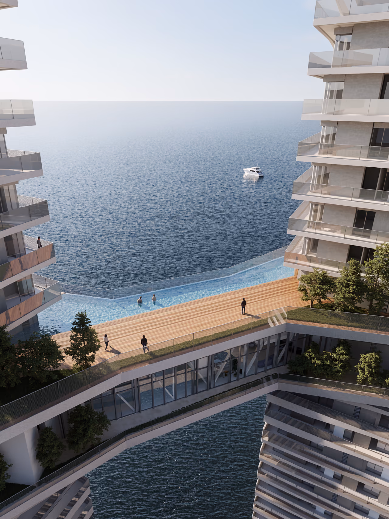 Infinity pool and wooden deck bridging the towers of Trilliant in Dubai, overlooking the sea with a yacht anchored offshore