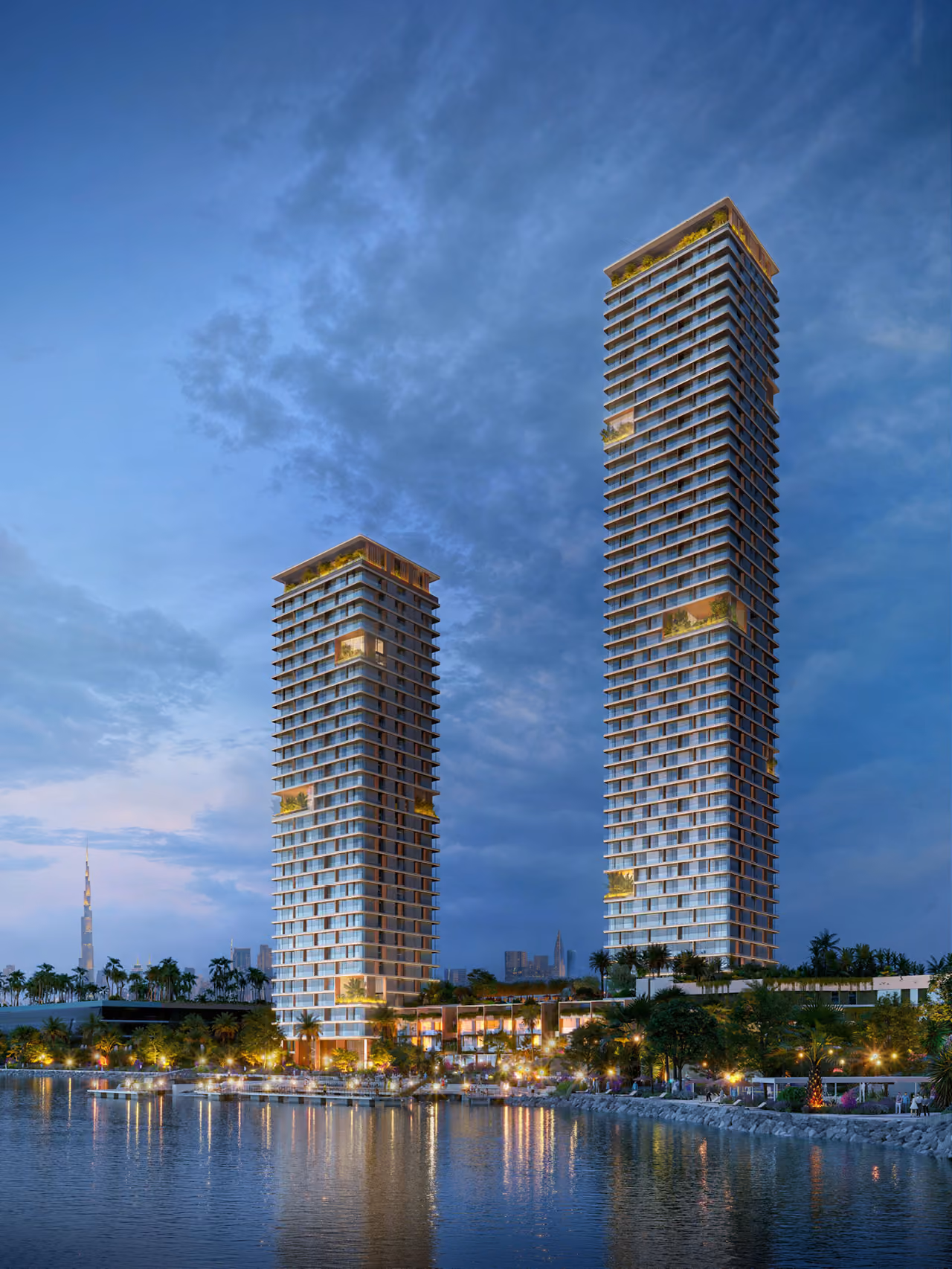 Twin residential towers of Orise in Dubai lit at dusk, waterfront setting with palm trees and the distant Burj Khalifa skyline