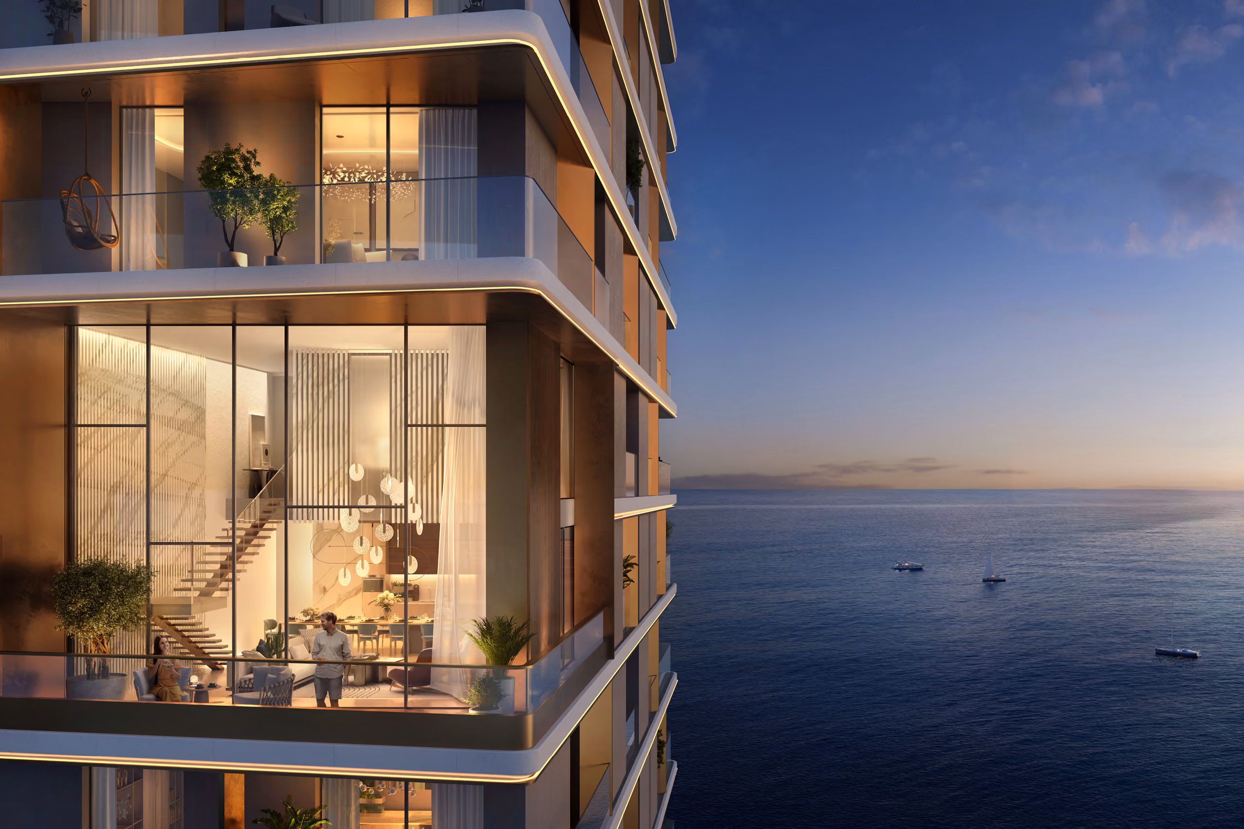 Duplex apartment terraces at Orise in Dubai glow warmly at dusk, illuminated interiors and staircases visible behind glazing overlooking a calm sea