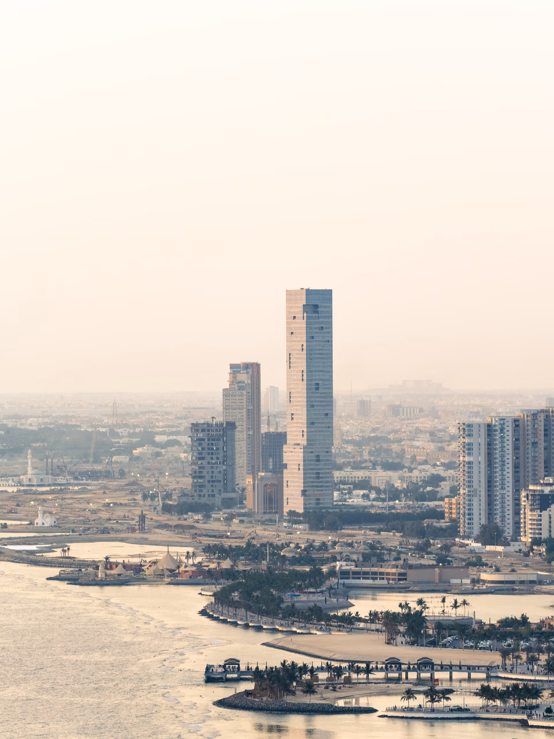 Aerial view of Golden Tower rising above Jeddah's coastline, its slender form standing out among lower buildings along the corniche and lagoon